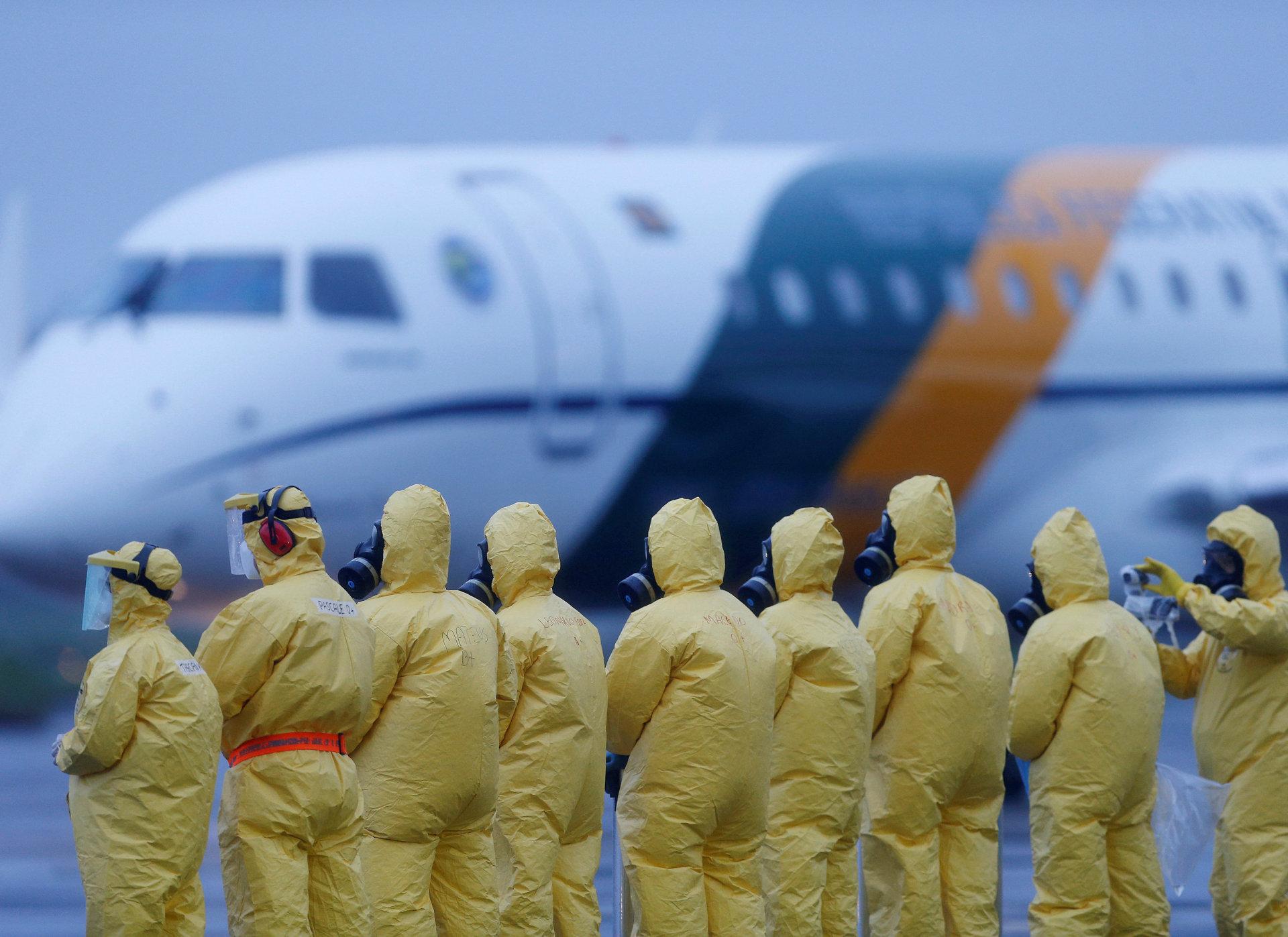 Soldater i vernedrakter venter på evakuerte brasilianere fra byen Wuhan i Kina. Bildet er tatt 9. februar ved Annapolis flybase i staten Goias i Brasil. Foto: Beto Barata/NTB Scanpix