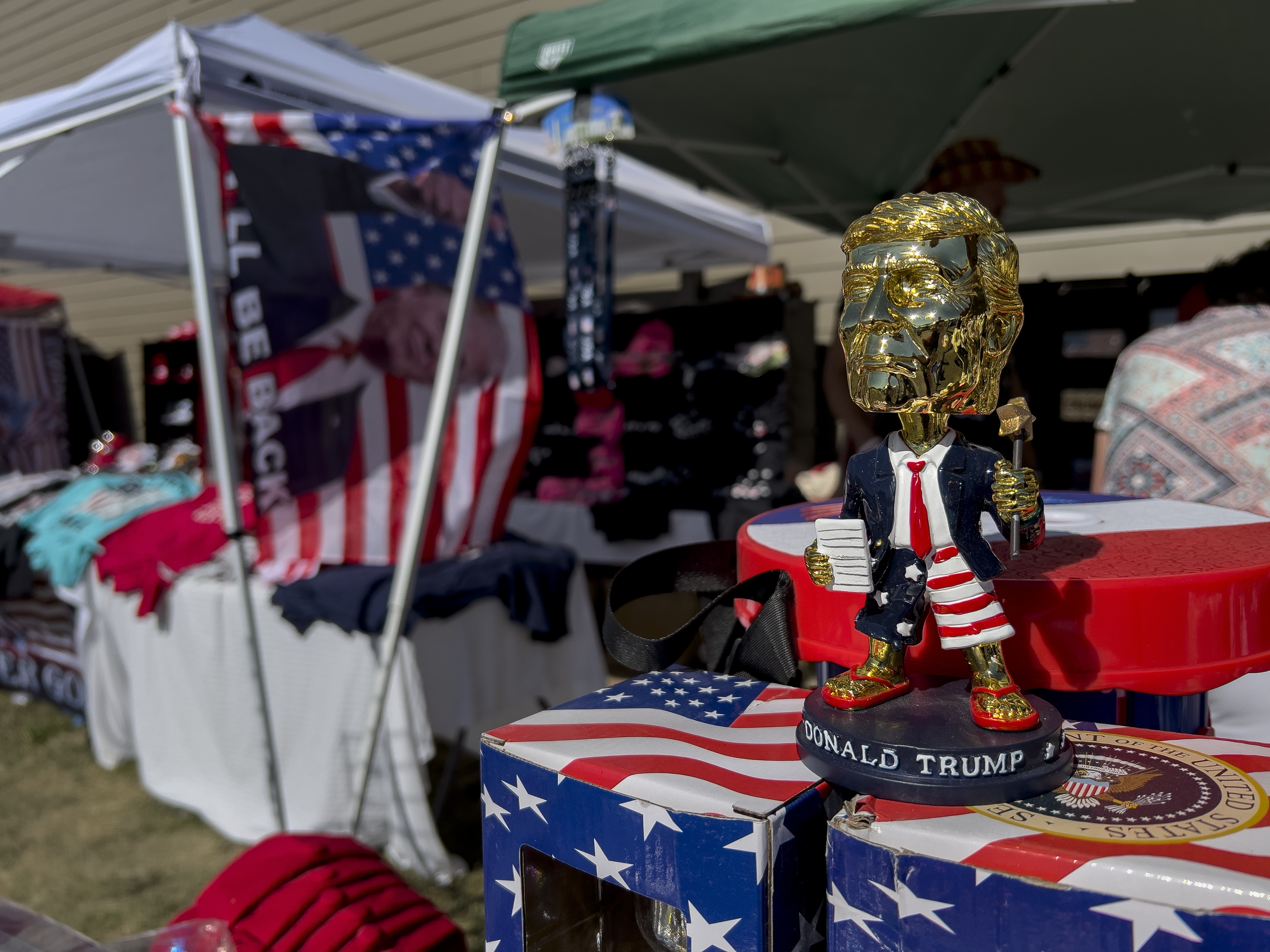 TRUMP-VENNLIGE: Et gullfarget boblehode av tidligere president Donald Trump og andre varer selges under ReAwaken America Tour.