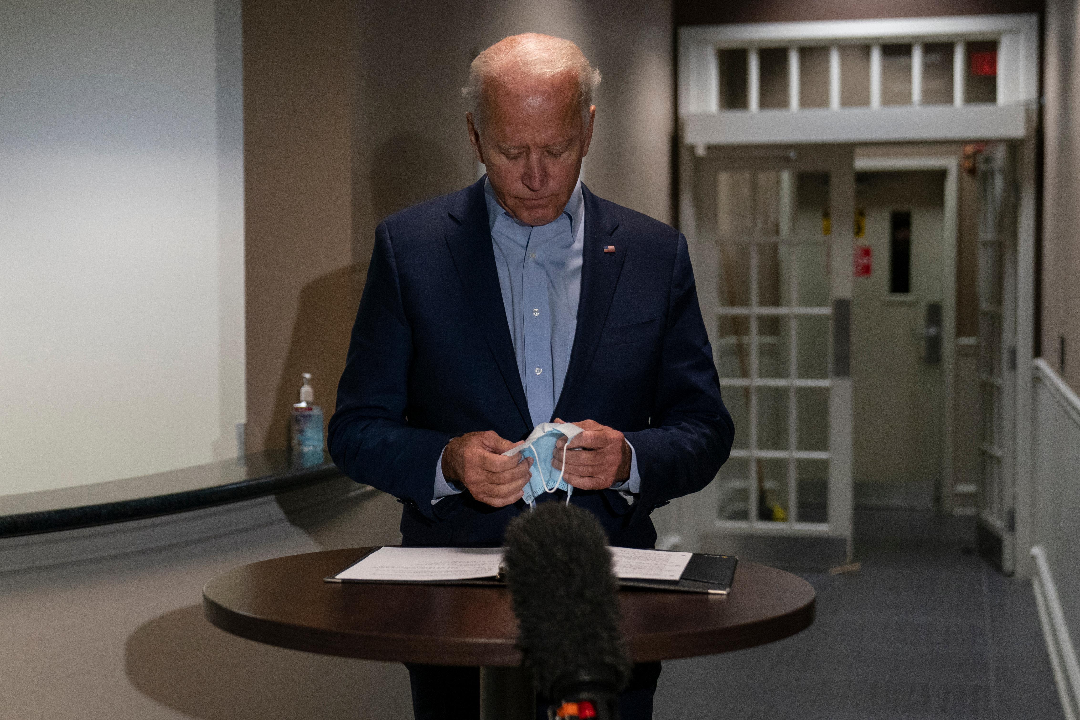 Democratic presidential candidate former Vice President Joe Biden pauses with his face mask in his hands as he speaks about the death of Supreme Court Justice Ruth Bader Ginsburg after he arrives at at New Castle Airport, in New Castle, Del., Friday, Sept. 18, 2020, as he returns from Duluth, Minn. (AP Photo/Carolyn Kaster)