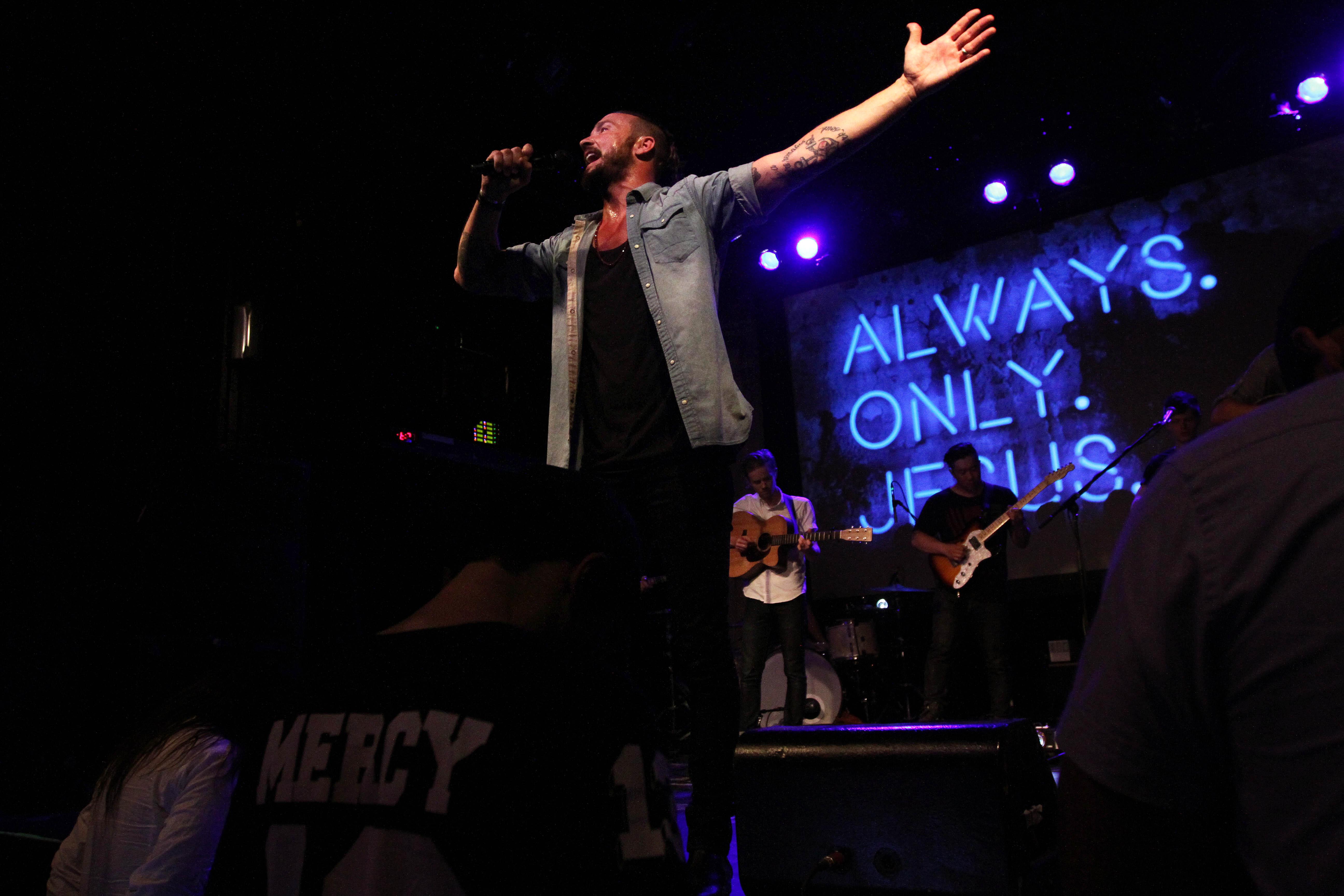 In this July 14, 2013 photo, Pastor Carl Lentz leads a Hillsong NYC Church service at Irving Plaza in New York. With his half-shaved head, jeans and tattoos, Lentz doesn't look like the typical religious leader. But with its concert-like atmosphere and appeal to a younger demographic, his congregation, Hillsong NYC, is one of the fastest growing evangelical churches in the city. (AP Photo/Tina Fineberg)