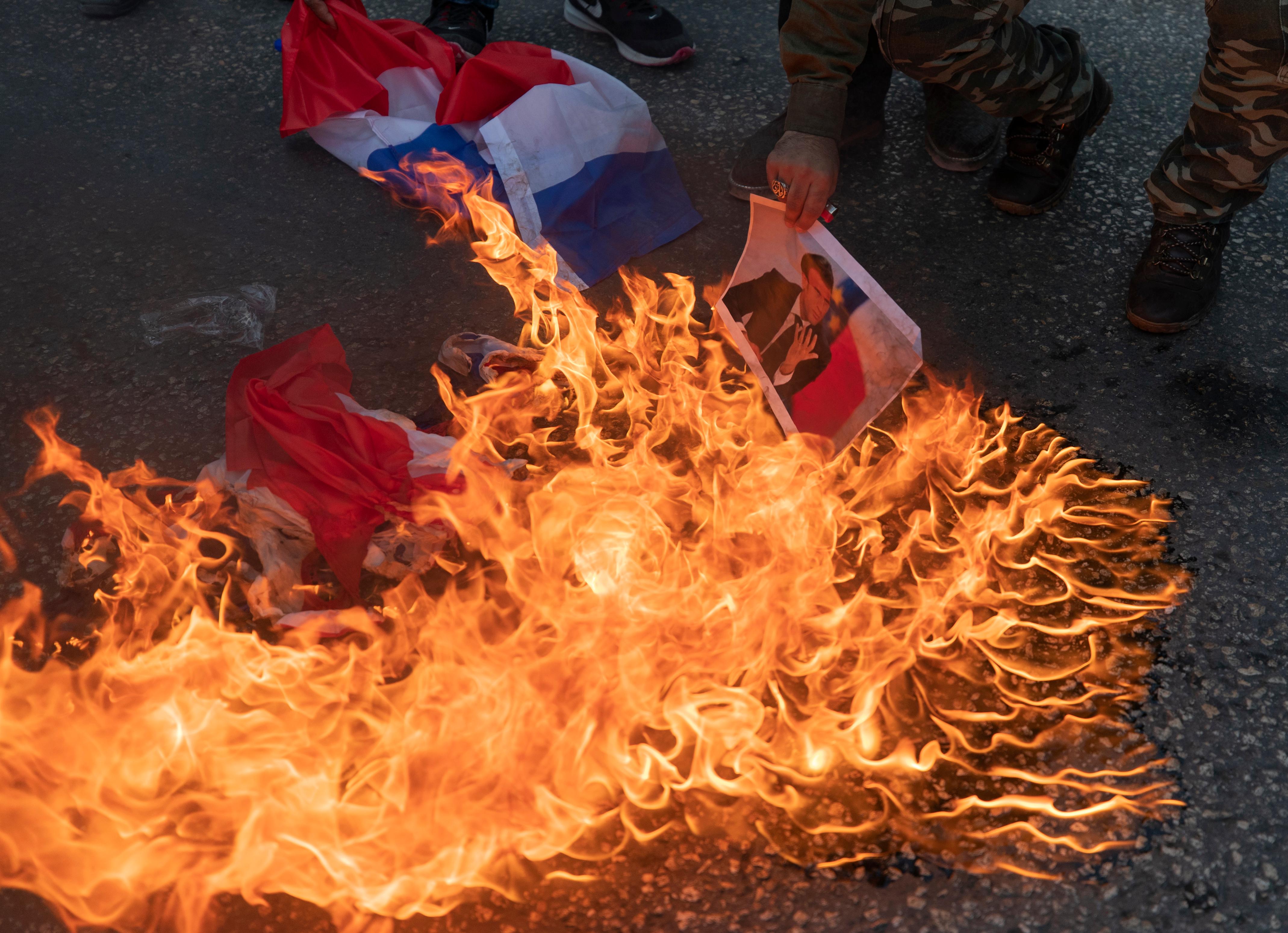 Palestinian protesters burn representa French flags and pictures of French President Emmanuel Macron during a protest against the publishing of caricatures of the Prophet Muhammad they deem blasphemous, in the West Bank city of Ramallah, Tuesday, Oct. 27, 2020.