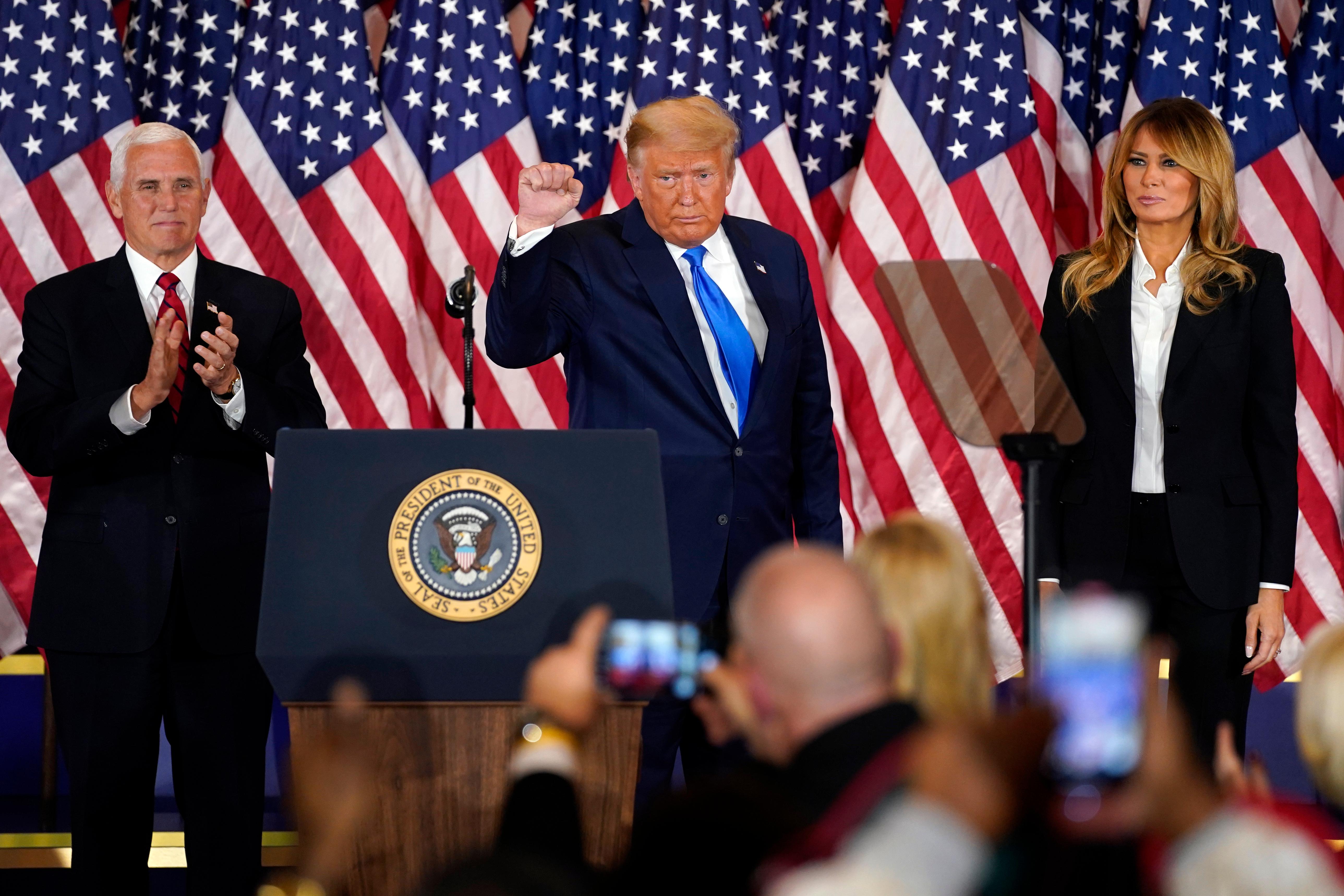 President Donald Trump pumps his fist after speaking in the East Room of the White House, early Wednesday, Nov. 4, 2020, in Washington, as Vice President Mike Pence and first lady Melania Trump watch. (AP Photo/Evan Vucci)