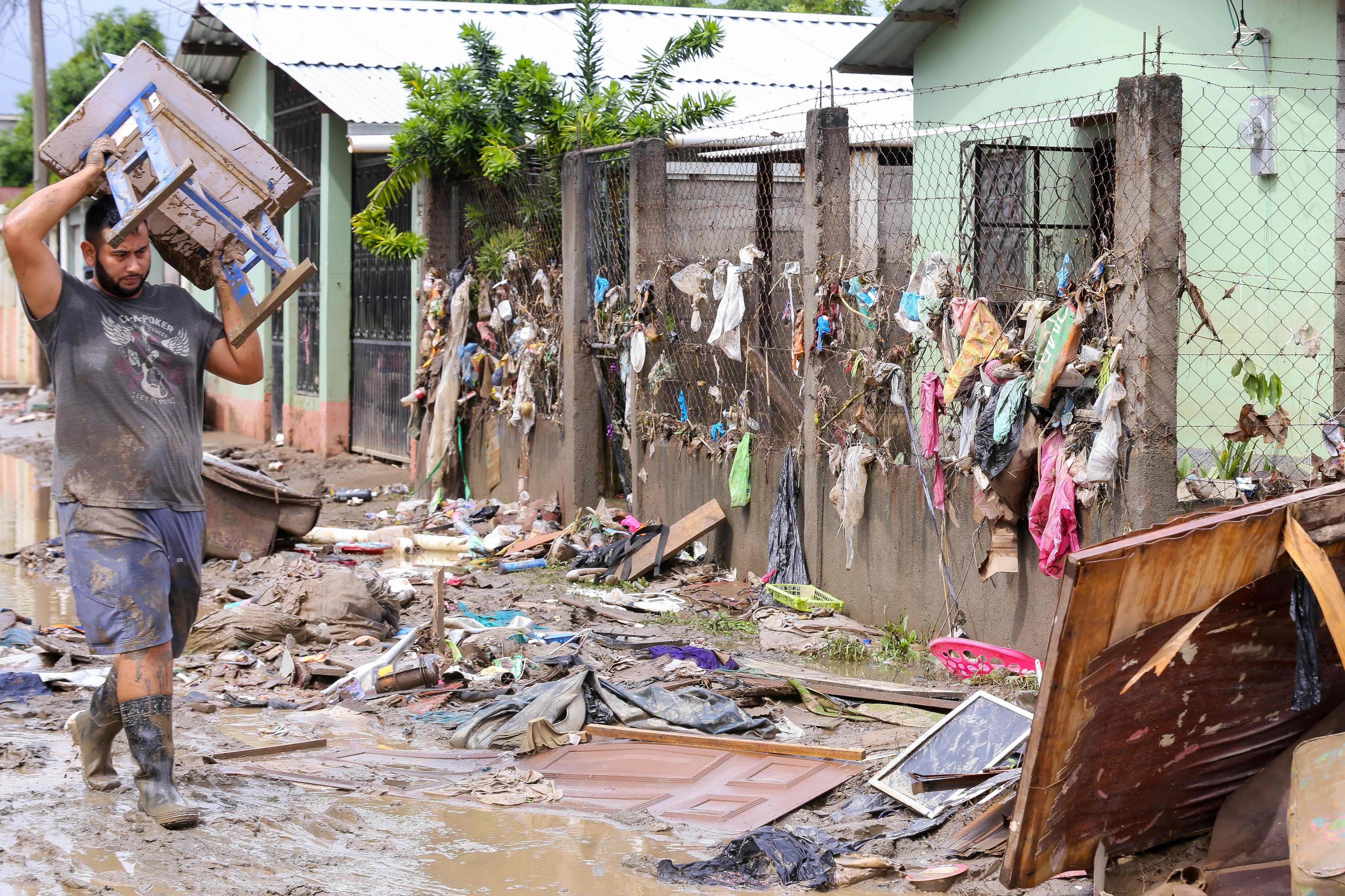 A man attempts to recover belongings amid mud and debris left by the overflowing of the Chamelecon River following heavy rains caused by Hurricane Iota, in La Lima municipality near San Pedro Sula, Honduras on November 21, 2020. - Rescue workers dug through mounds of thick mud in the grim search for bodies as Central American countries began to count the cost of Hurricane Iota, which left at least 44 people dead amid a wave of destruction. Initial estimates by the United Nations Children's Fund, UNICEF, put the number of people affected by the hurricane at 4.6 million across the impoverished region, including 1.8 million children. (Photo by Wendell ESCOTO / AFP)