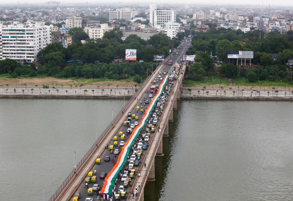 Bildet viser et stort indisk flagg som bæres over elva Sabarmati i Ahmadabad