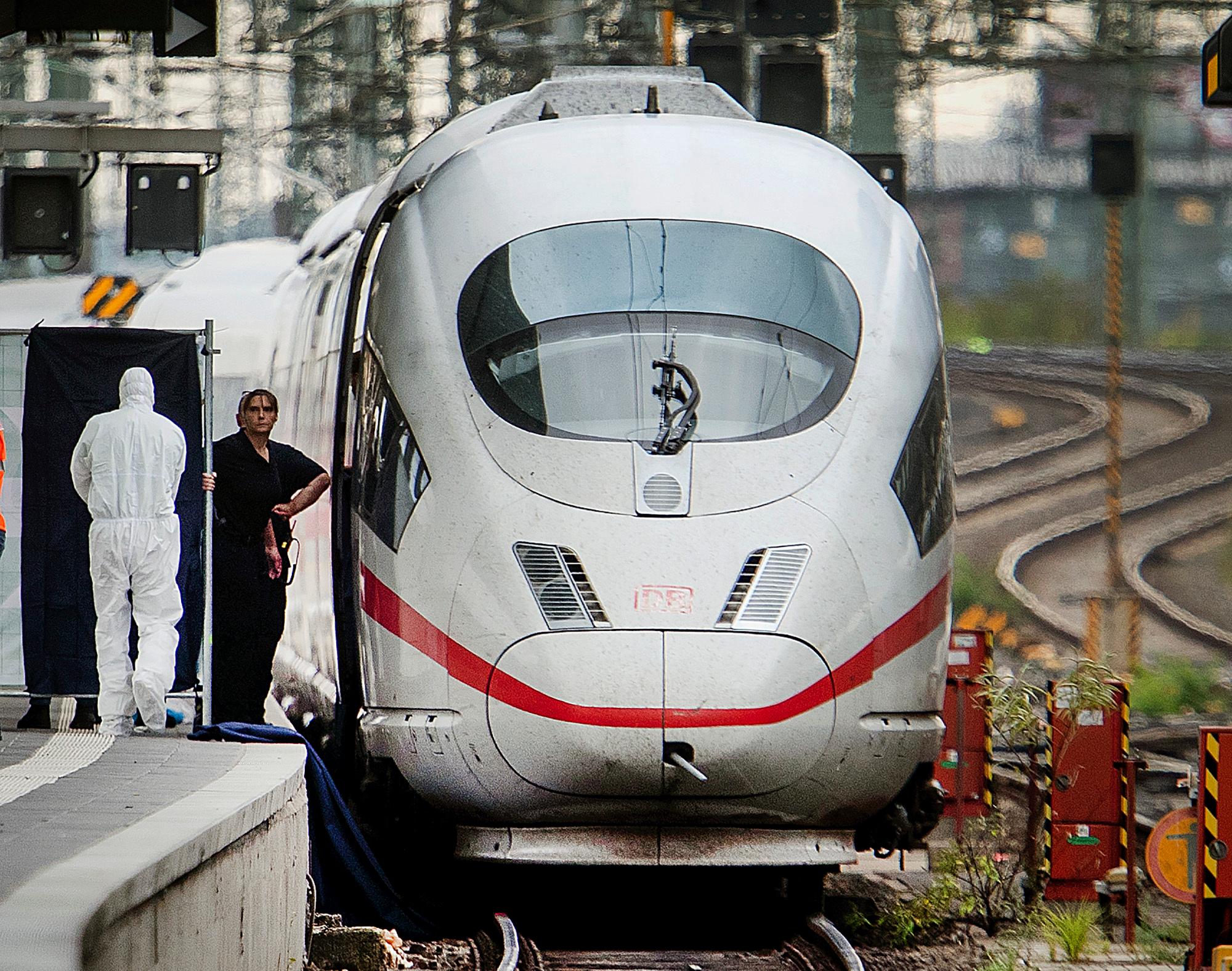 Police officers and rescue workers recover a body under an ICE highspeed train at the main station in Frankfurt, Germany, Monday, July 29, 2019. An 8-year-old boy was run over by a train and killed at Frankfurt's main station on Monday after a man pushed him and his mother onto the tracks. The mother was able to escape but the boy was hit and run over by the train and suffered fatal injuries. (AP Photo/Michael Probst)