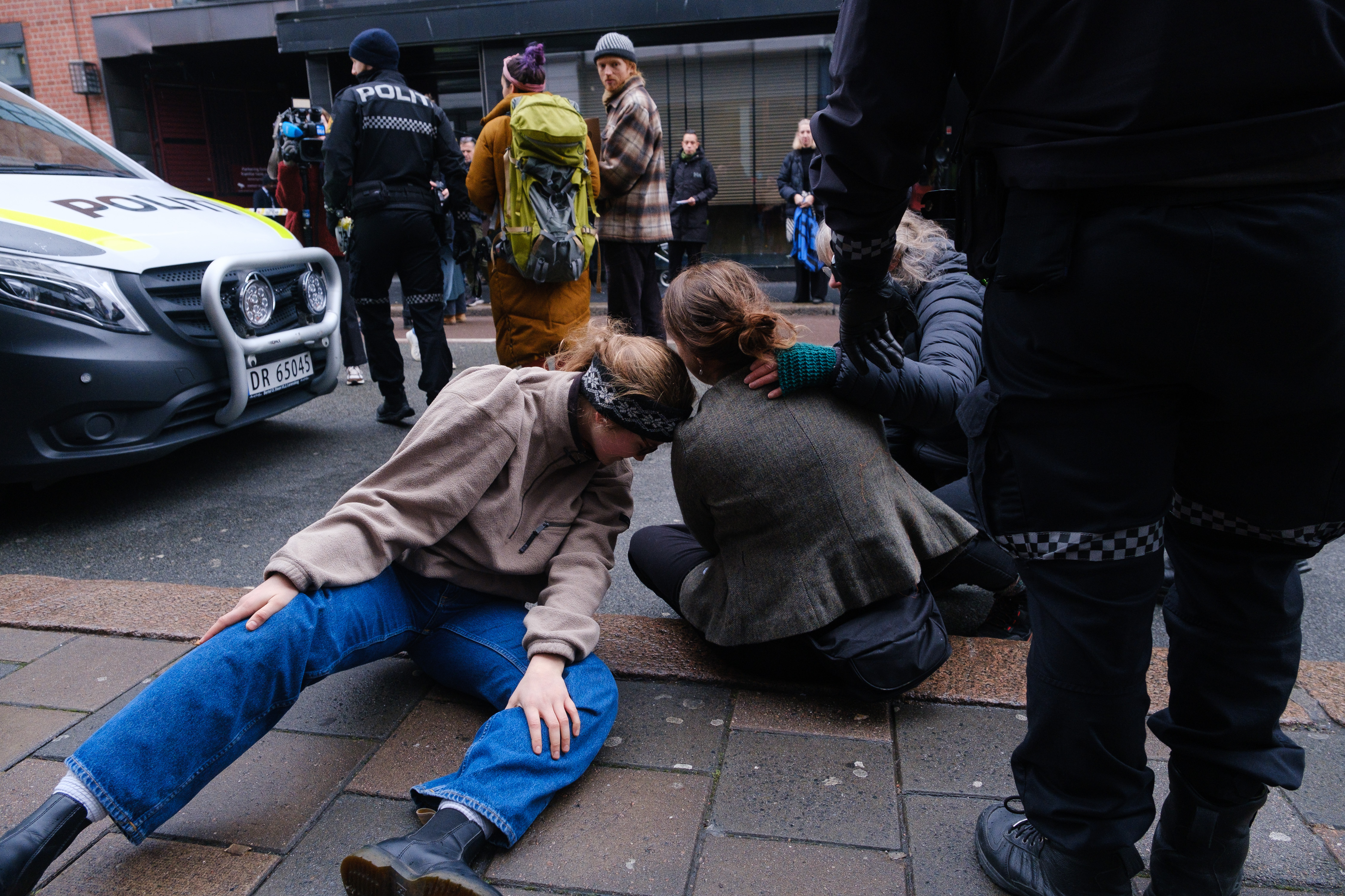 To Extinction Rebellion-aktivister trøster hverandre mens de venter på politibilen som skal frakte dem til sentralarresten på Grønland.