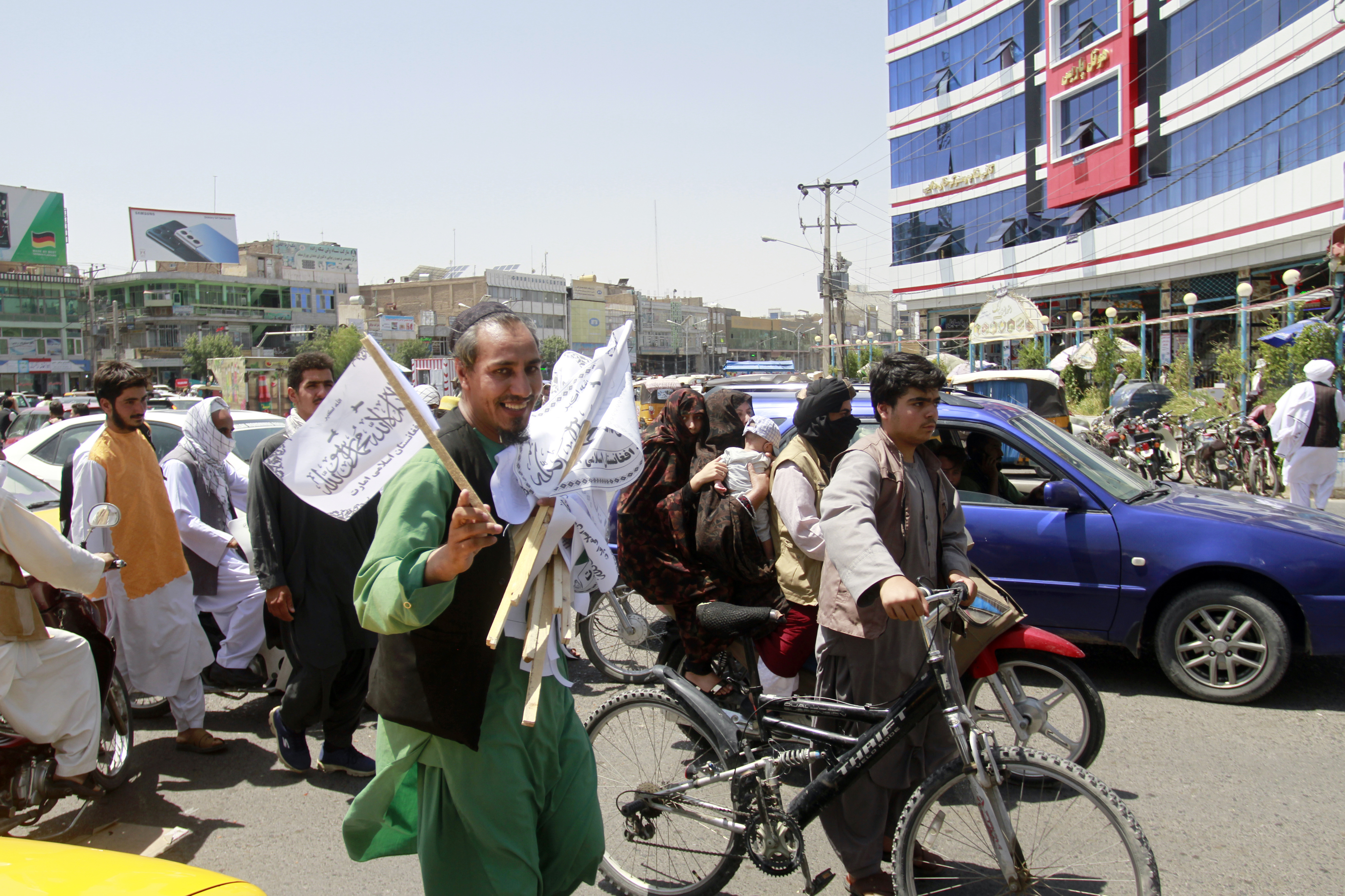 En mann deler ut Taliban-flagg i gatene i Herat for å feire at Taliban har tatt kontroll over store deler av Afghanistan og søndag var i forhandlinger om en maktoverføring. Foto: Hamed Sarfarazi / AP / NTB