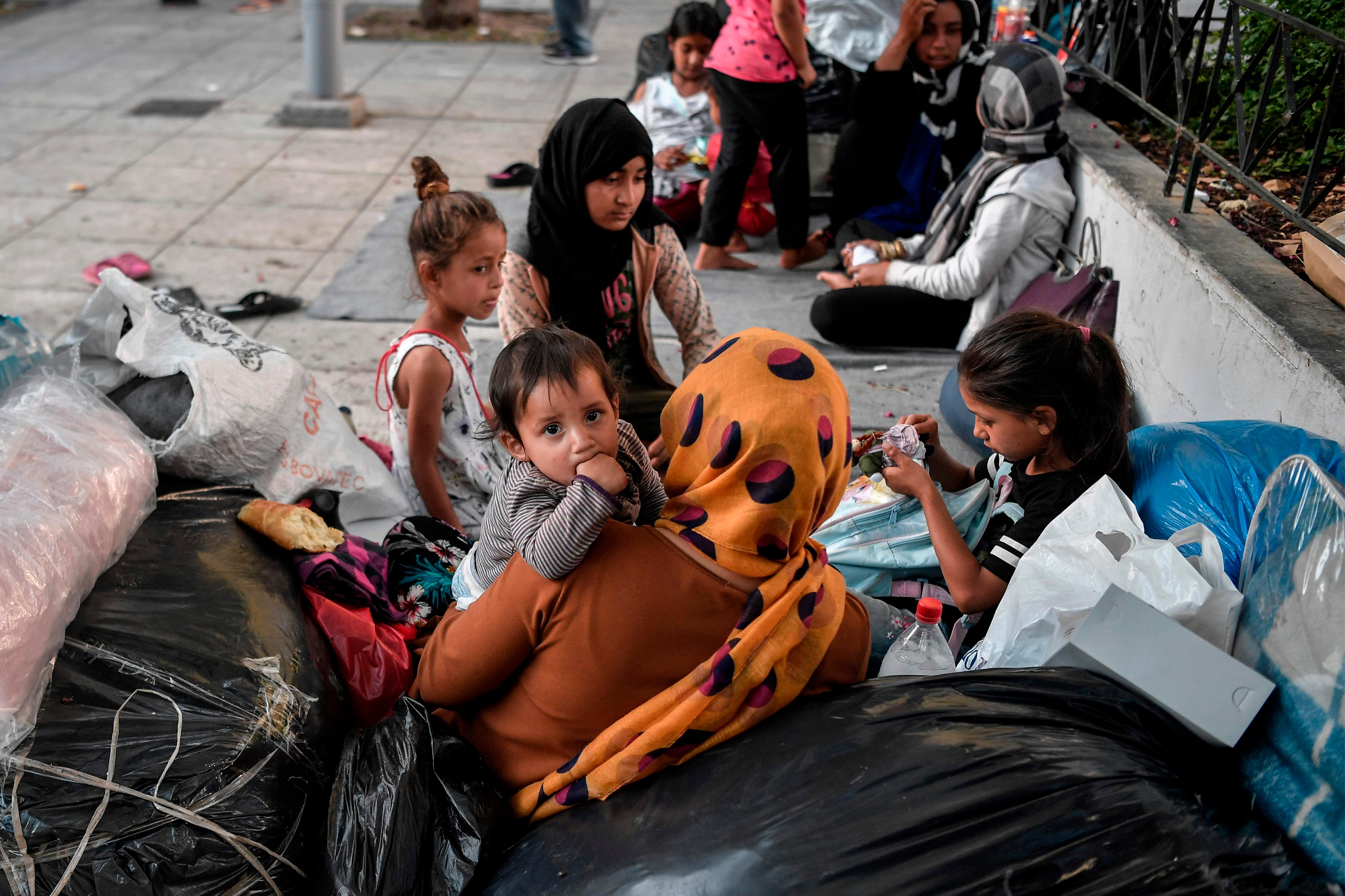 A child looks on as Afghan families who arrived, from Moria camp on the island of Lesbos camp, at an central Athens square on June 14, 2020 after receiving a blue stamp which allowed them to travel to the mainland. - At least 66 refugees, who arrived from the island after their asylum applications where approved, camp on the square as they have no place to stay in Athens. (Photo by Louisa GOULIAMAKI / AFP)