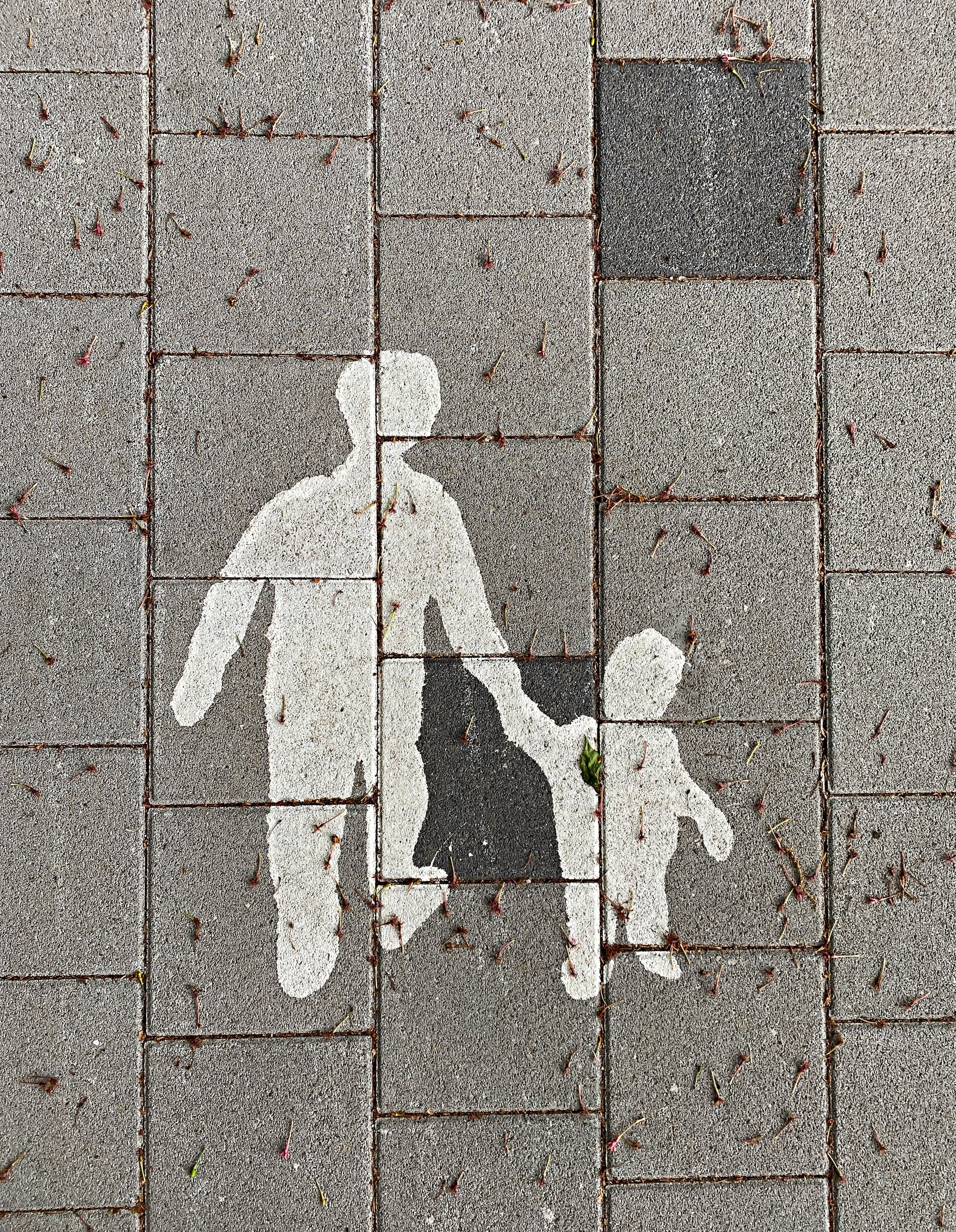 Målning på vägbanan, vuxen håller ett barn i handen.