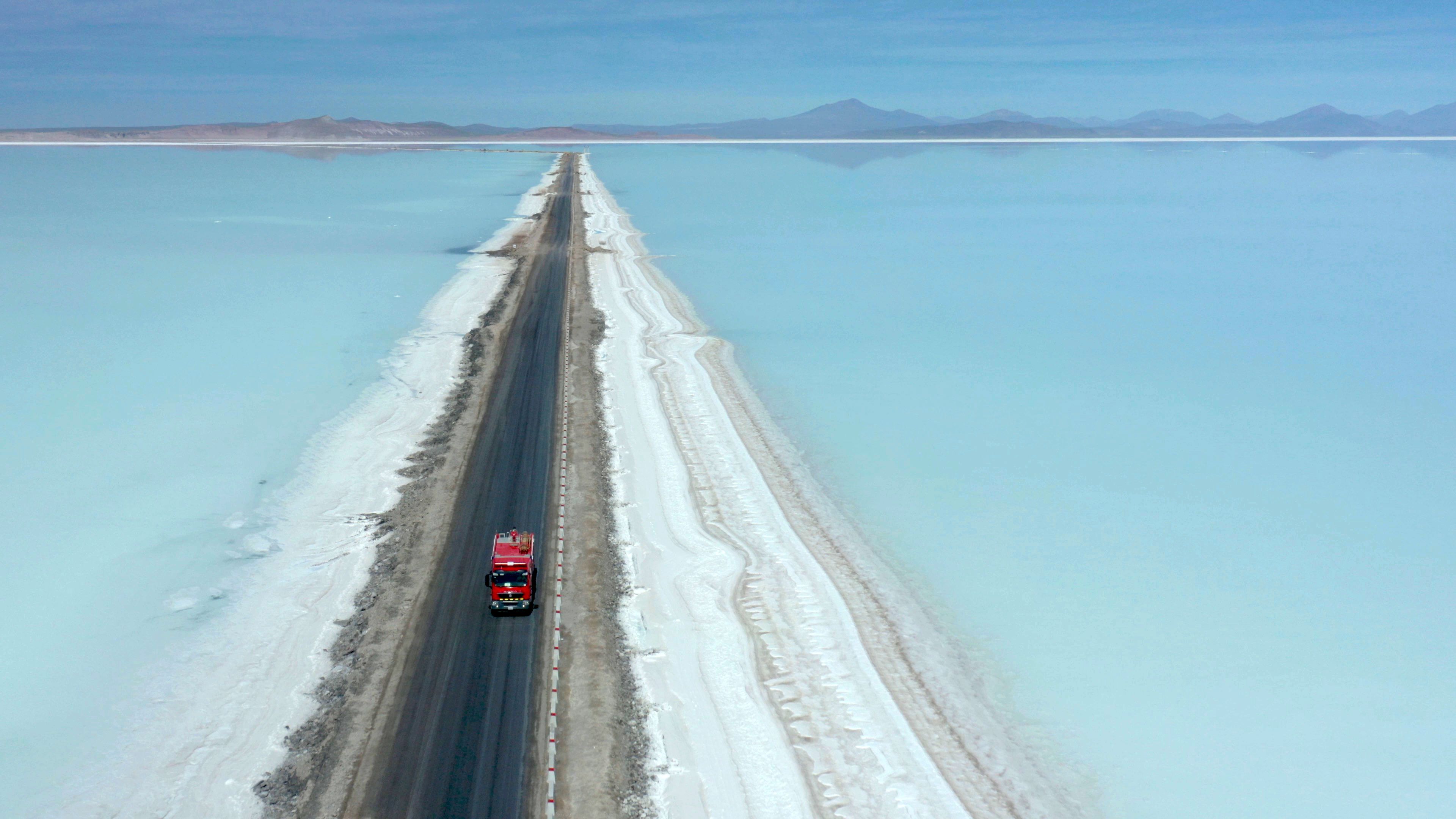 En lastebil kjører på en vei gjennom en slette med saltlake der litium utvinnes i Uyuni i Bolivia.