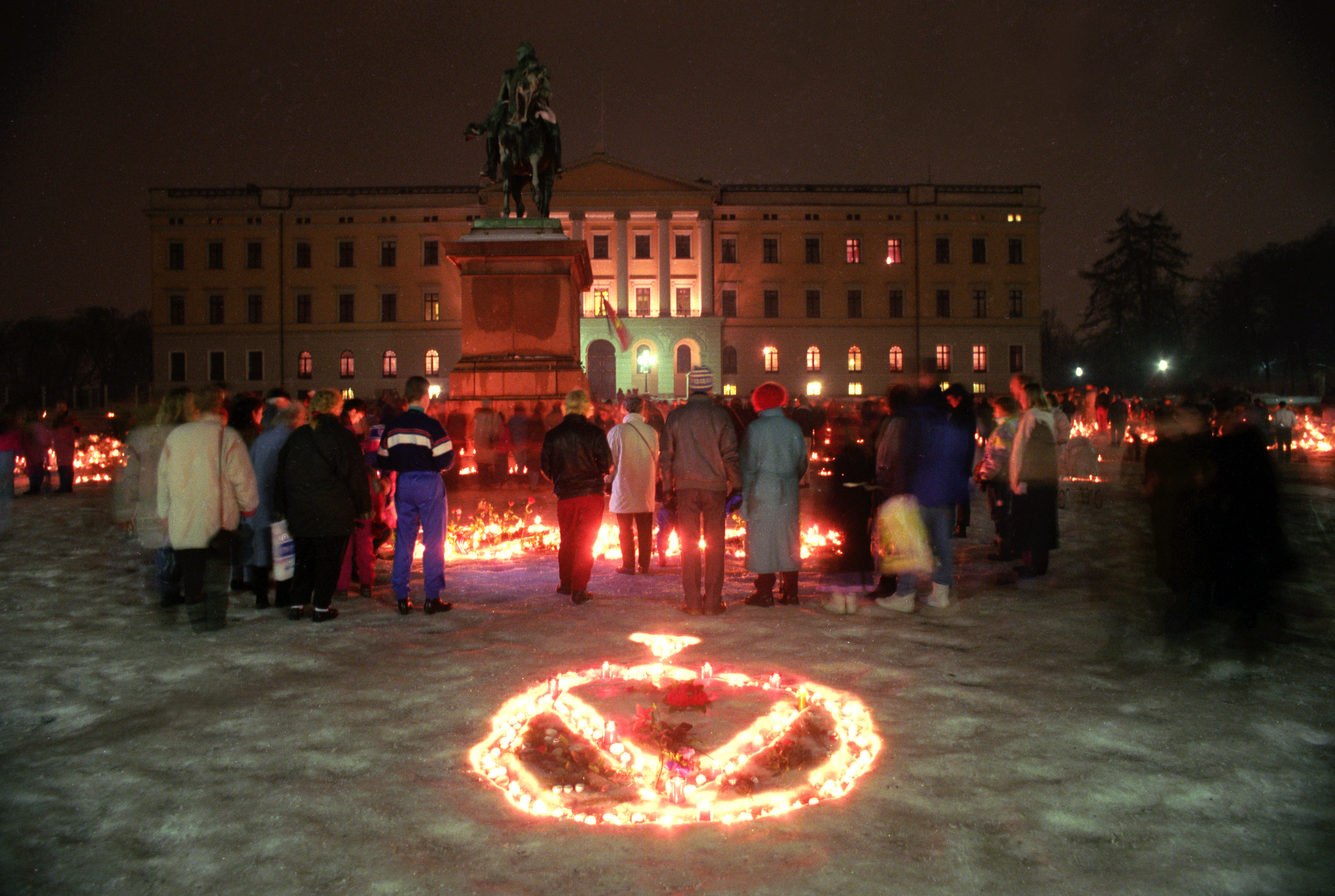 Folk samler seg på Slottsplassen. Sørgende mennesker tenner lys, skriver hilsener og legger ned blomster på Slottsplassen. Kongens monogram i levende lys på Slottsplassen.