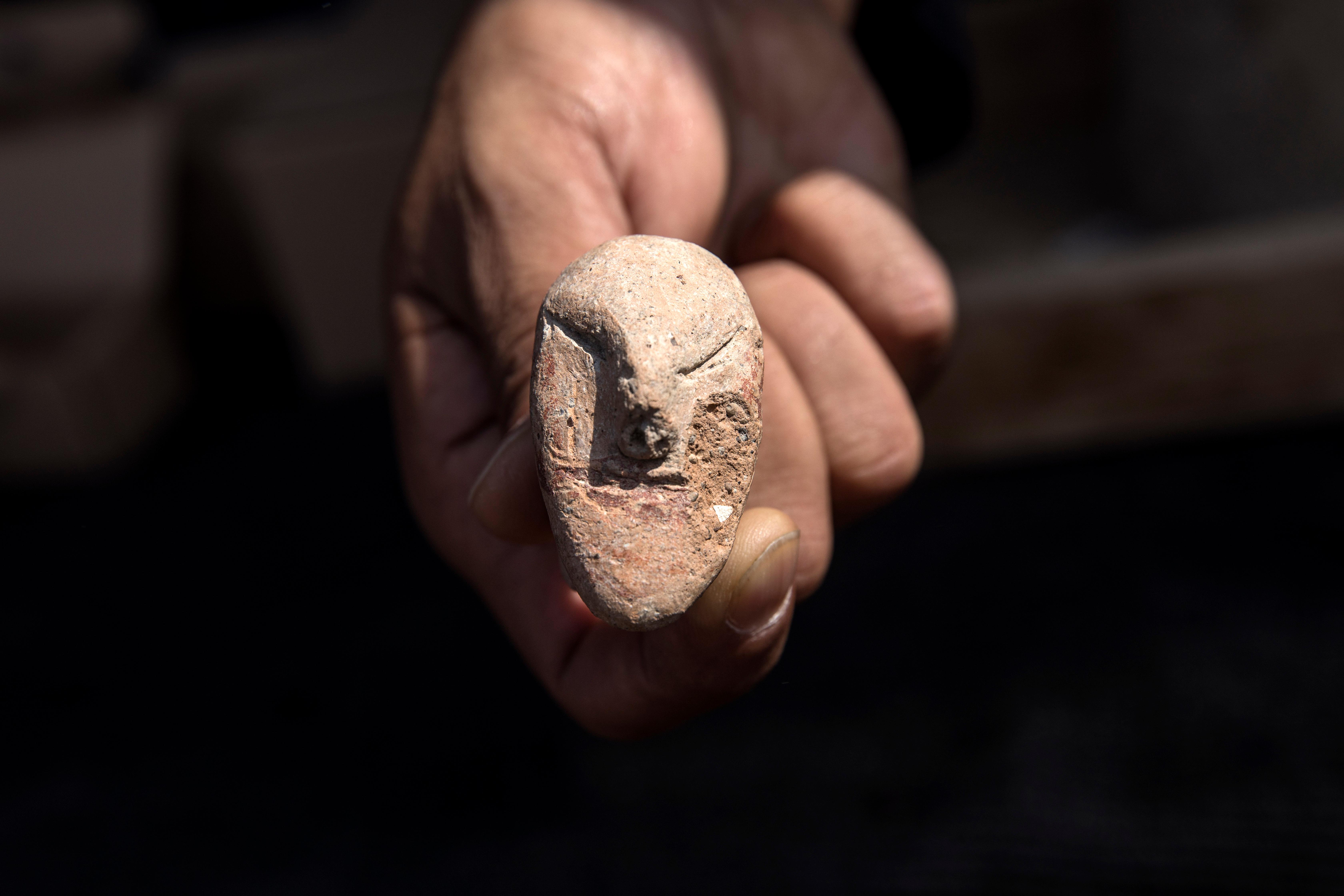 An archeologists shows a figurine found at a large, 5,000-year-old city in northern Israel. Israel's Antiquities Authority said Sunday the ancient city was discovered during preparations for a new highway interchange near Harish, a town roughly 50 kilometers (30 miles) north of Tel Aviv, Sunday, Oct. 6, 2019. (AP Photo/Tsafrir Abayov)