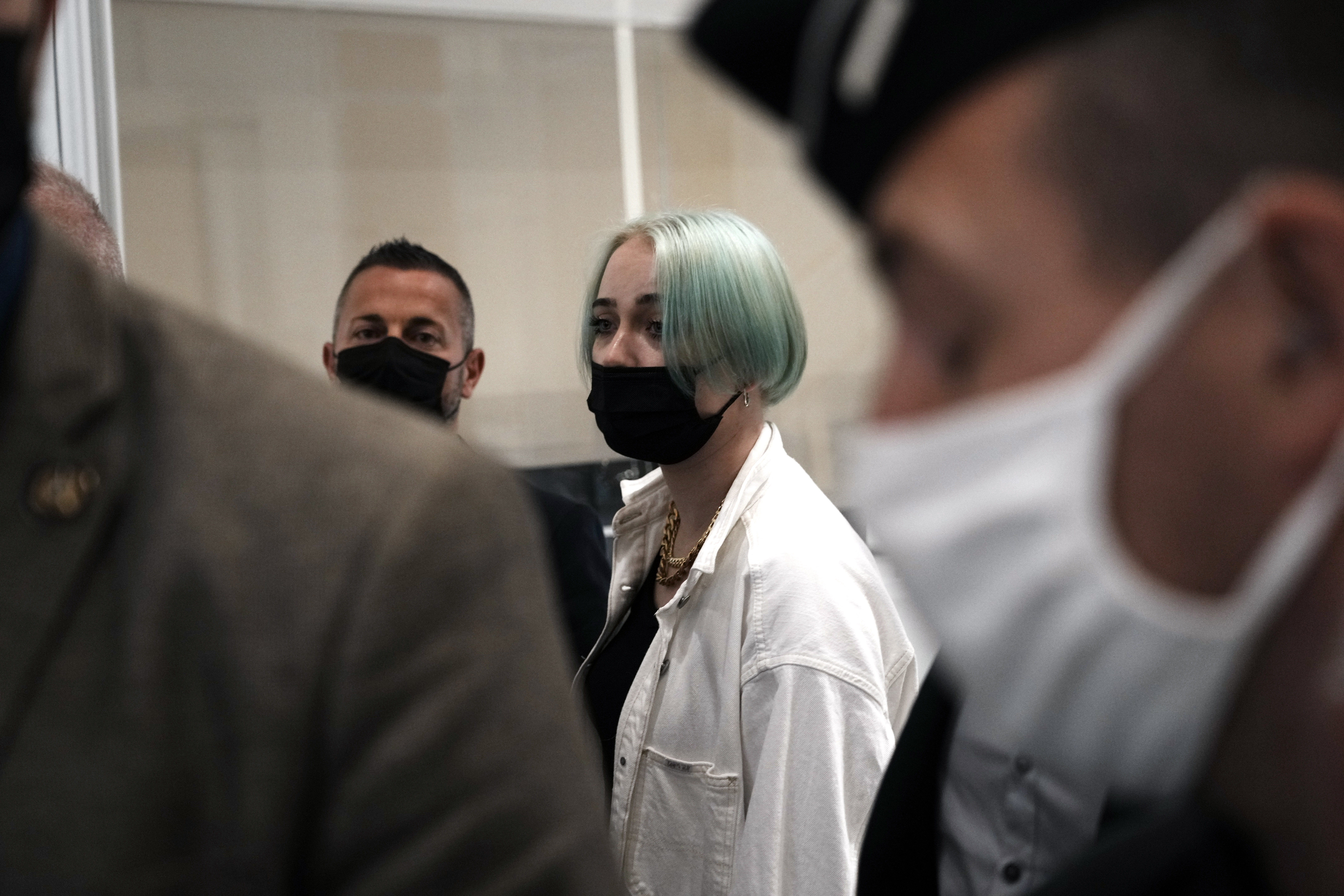 The teenager identifying herself online as Mila, center right, leaves the courtroom Monday, June 21, 2021 in Paris. Thirteen people went on trial in Paris accused of cyberbullying or death threats against the teenage girl who posted comments online critical of Islam. (AP Photo/Thibault Camus)
