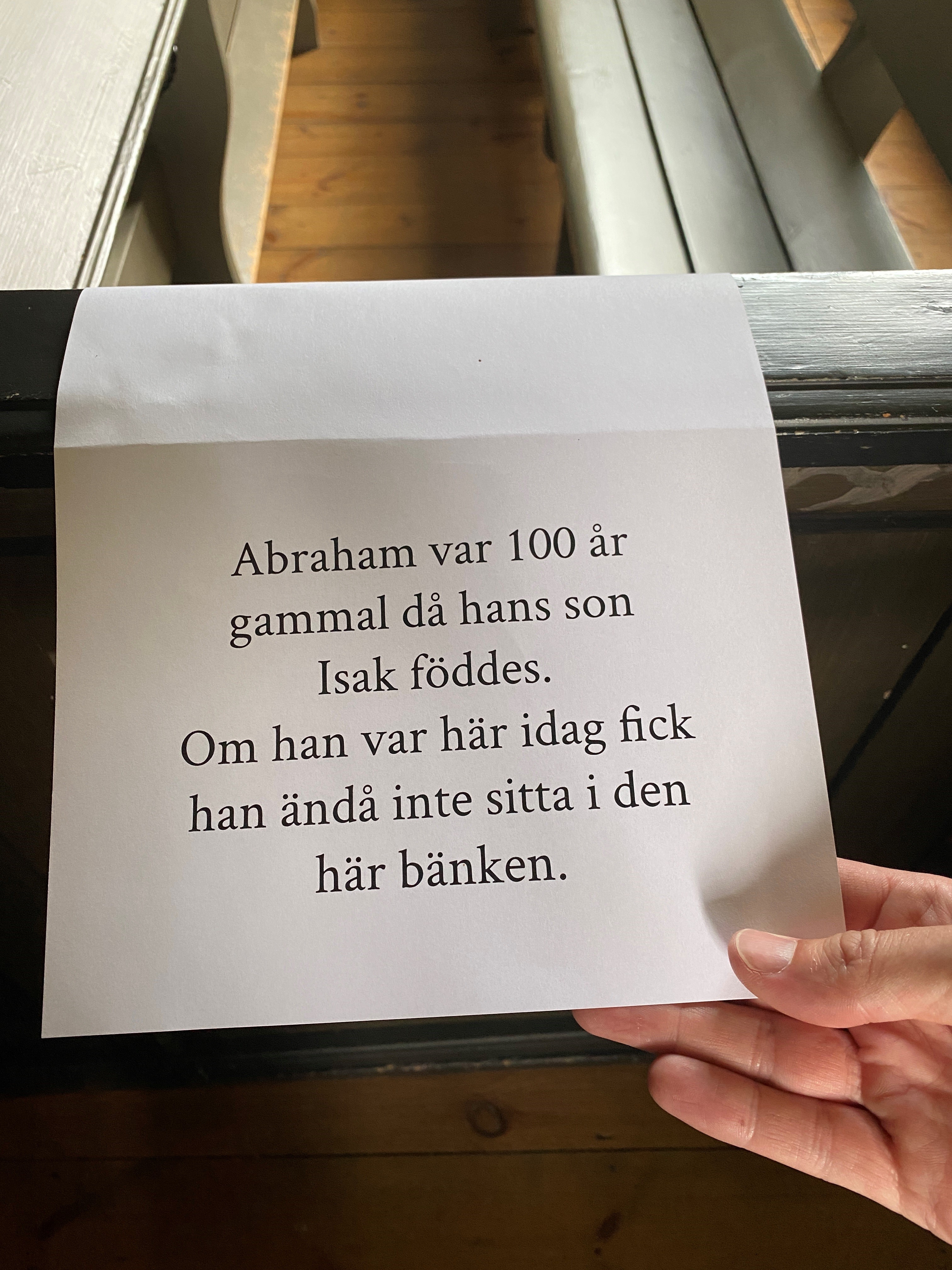 Bild på platsanvisning i Torpa kyrka med texten "Abraham var 100 år gammal då Isak föddes. Om han var här idag hade han ändå inte fått sitta i den här bänken."