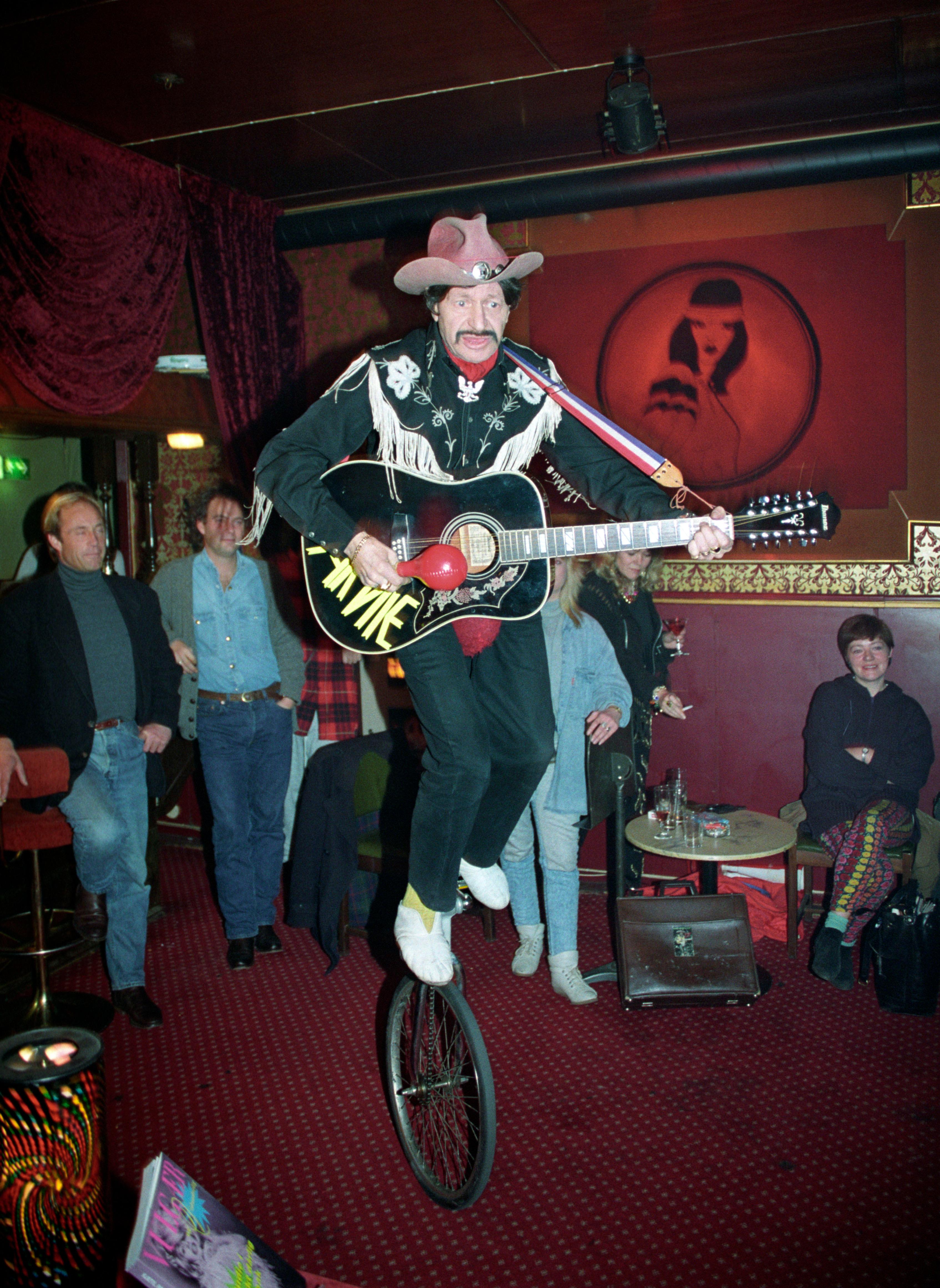 Oslo 19921120: Boken"Vulgær og Vidunderlig", forfattet av Kjetil Rolness, lanseres. Boken  omhandler begrepet "Kitsch & Camp". Bildet: Den lokale artisten Arnie Norse , også kjent som "Skiffle Joe" i kjent stil med sang og gitarspill på sin enhjulssykkel.  (Sted: Original Pilsen, Oslo.) FOTO: Per Flaathe