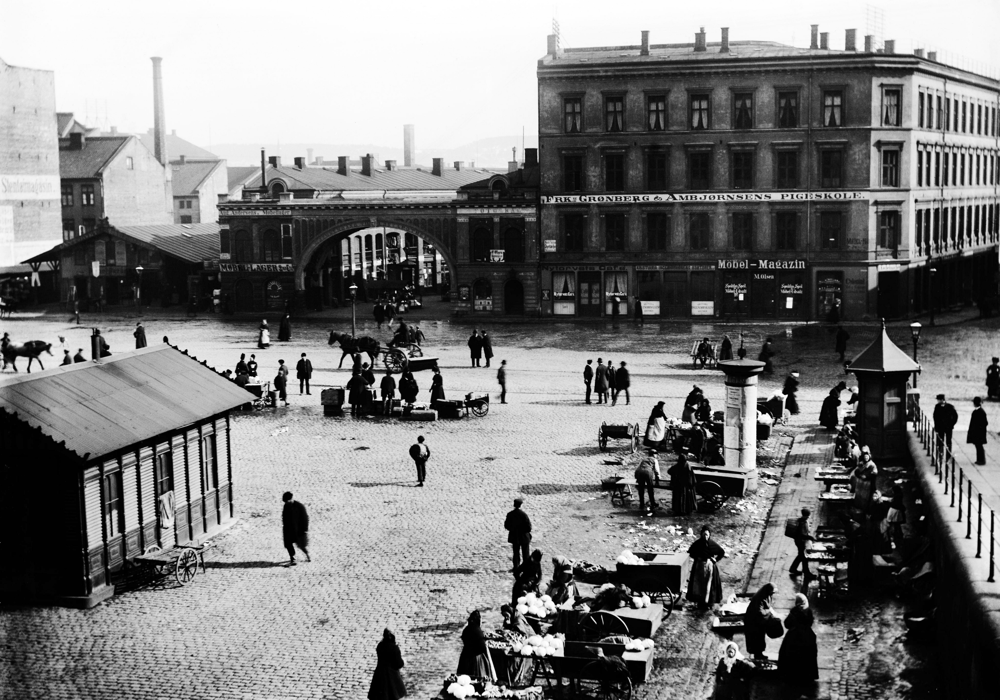 YOUNGSTORGET CIRKA 1900: Langs muren under daværende Pløens gate, i dag Eva Kolstads gate, sto ifølge Haakon B. Nielson fiskekonene med blant annet store baljer lutefisk. Til venstre vekthuset. 