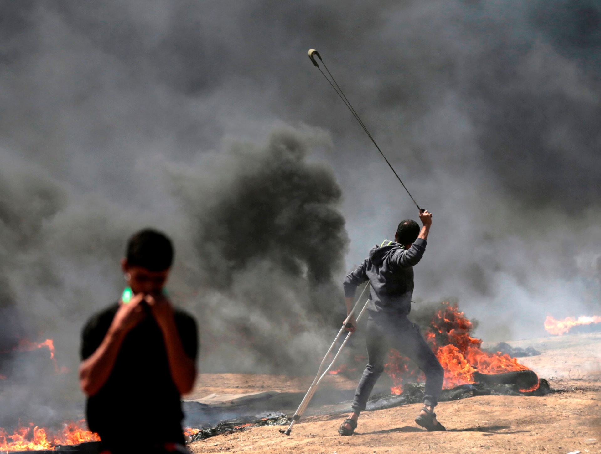 kaster stein: En palestiner kaster stein med slynge på de israelske styrkene ved grensa til Gaza. Mange av palestinerne som er drept og såret av israelske skudd er truffet på mange hundre meters hold. FOTO: NTB SCANPIX