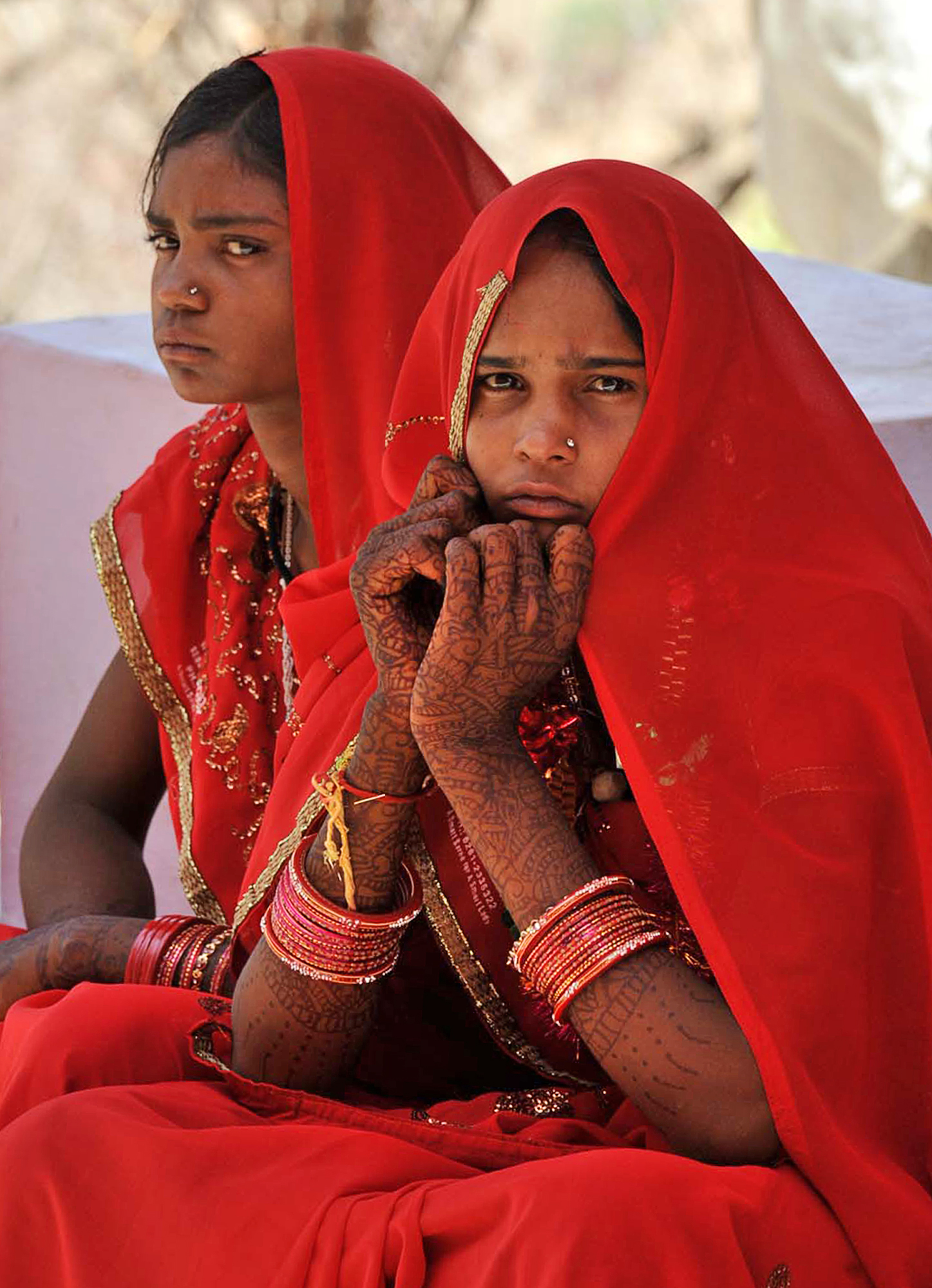 In this Friday, May 6, 2011 photo, child brides Chinti Bai, 12, left,  and Anita, 12, sit outside the Maa Jalapa Devi temple after their marriage ceremony in Rajgarh, about 155 kilometers (96 miles) from Bhopal, India. Ignoring laws that ban child marriages, several young children, are still married off as part of centuries-old custom in some Indian villages. India law prohibits marriage for women younger than 18 and men under age 21. (AP Photo/Prakash Hatvalne)
