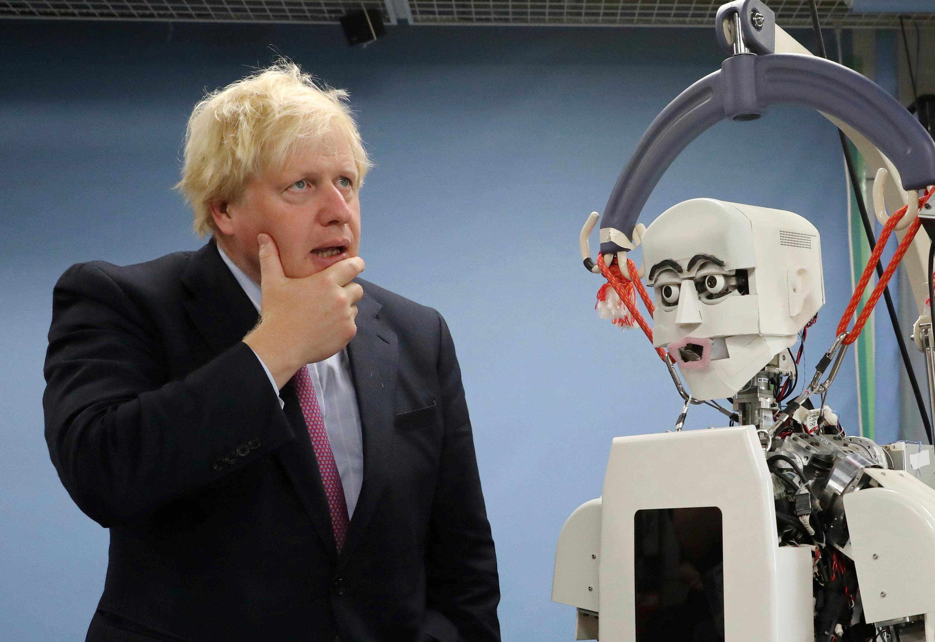 Britain's Foreign Secretary Boris Johnson gestures by a humanoid robot at Research Institute for Science and Engineering at Waseda University's campus in Tokyo Thursday, July 20, 2017. Johnson visited the robotics center at the university, which collaborates with the University of Birmingham. (AP Photo/Eugene Hoshiko, Pool)