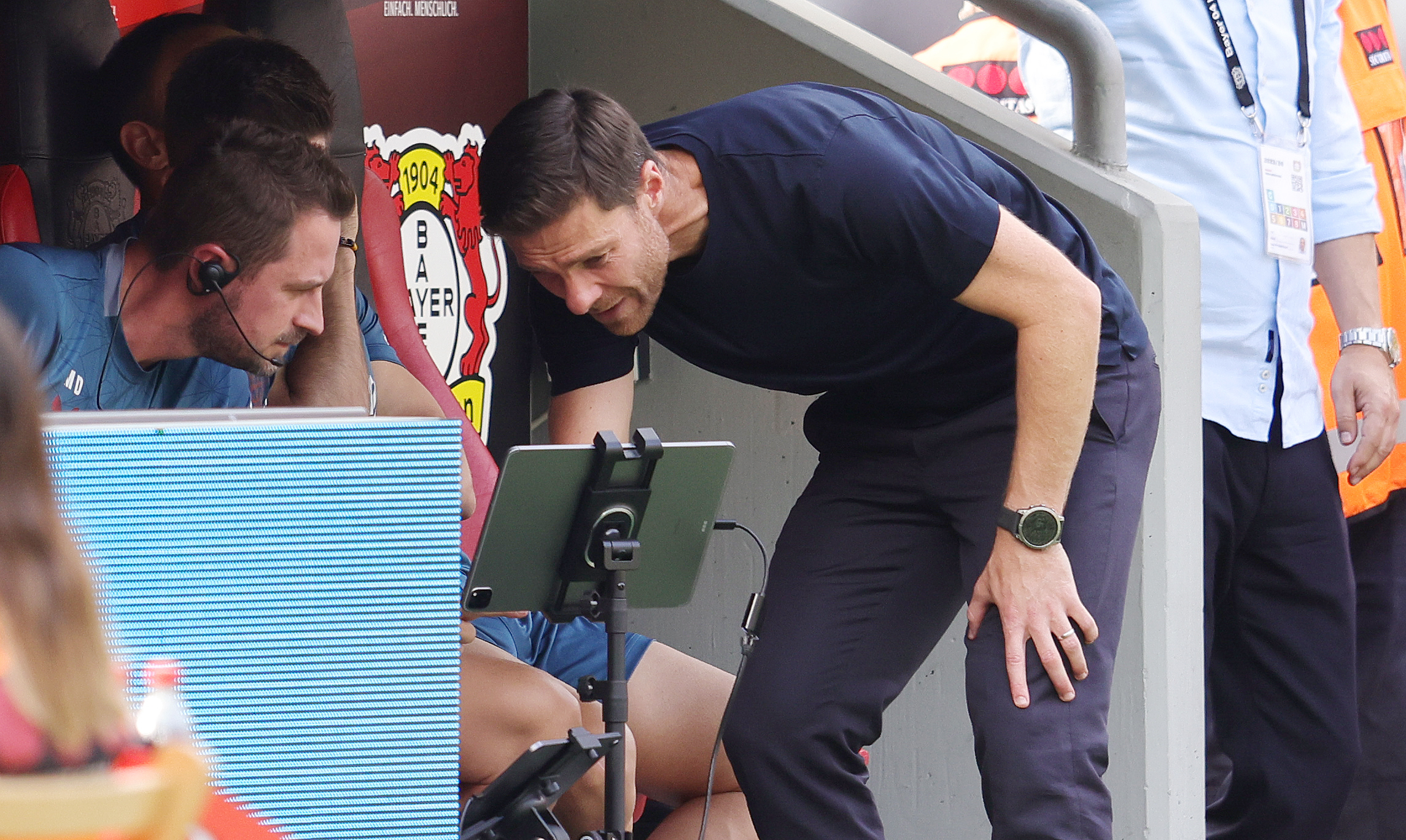Xabi Alonso, entrenador del Bayer Leverkusen observando un dispositivo junto a su asistente.