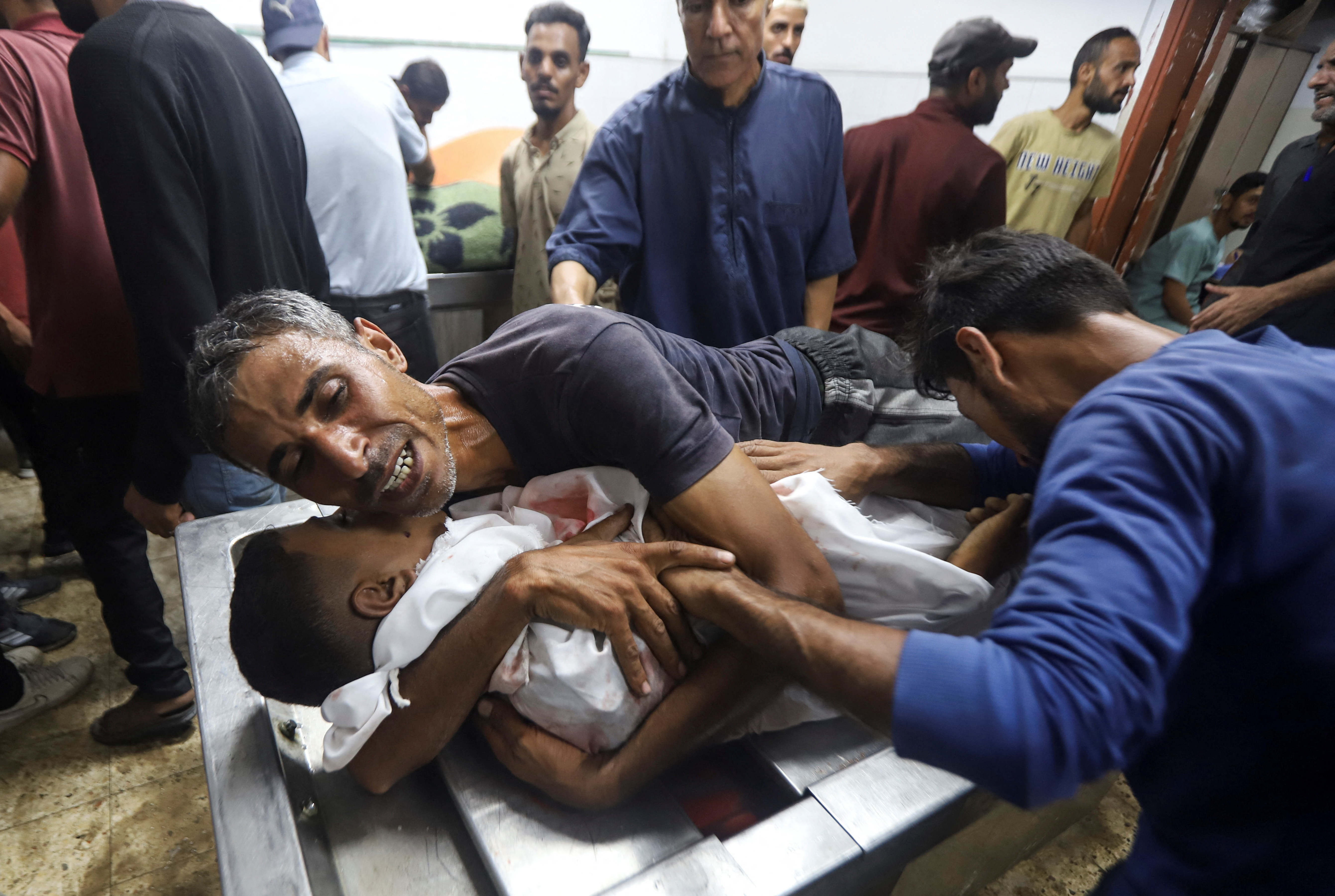 SENSITIVE MATERIAL. THIS IMAGE MAY OFFEND OR DISTURB A mourner hugs a body at the funeral of Palestinians, who, according to Gaza's health ministry, were killed in an Israeli air strike, at Al-Shifa Hospital, in Gaza City, June 25, 2025.  REUTERS/Khamis Al-Rifi