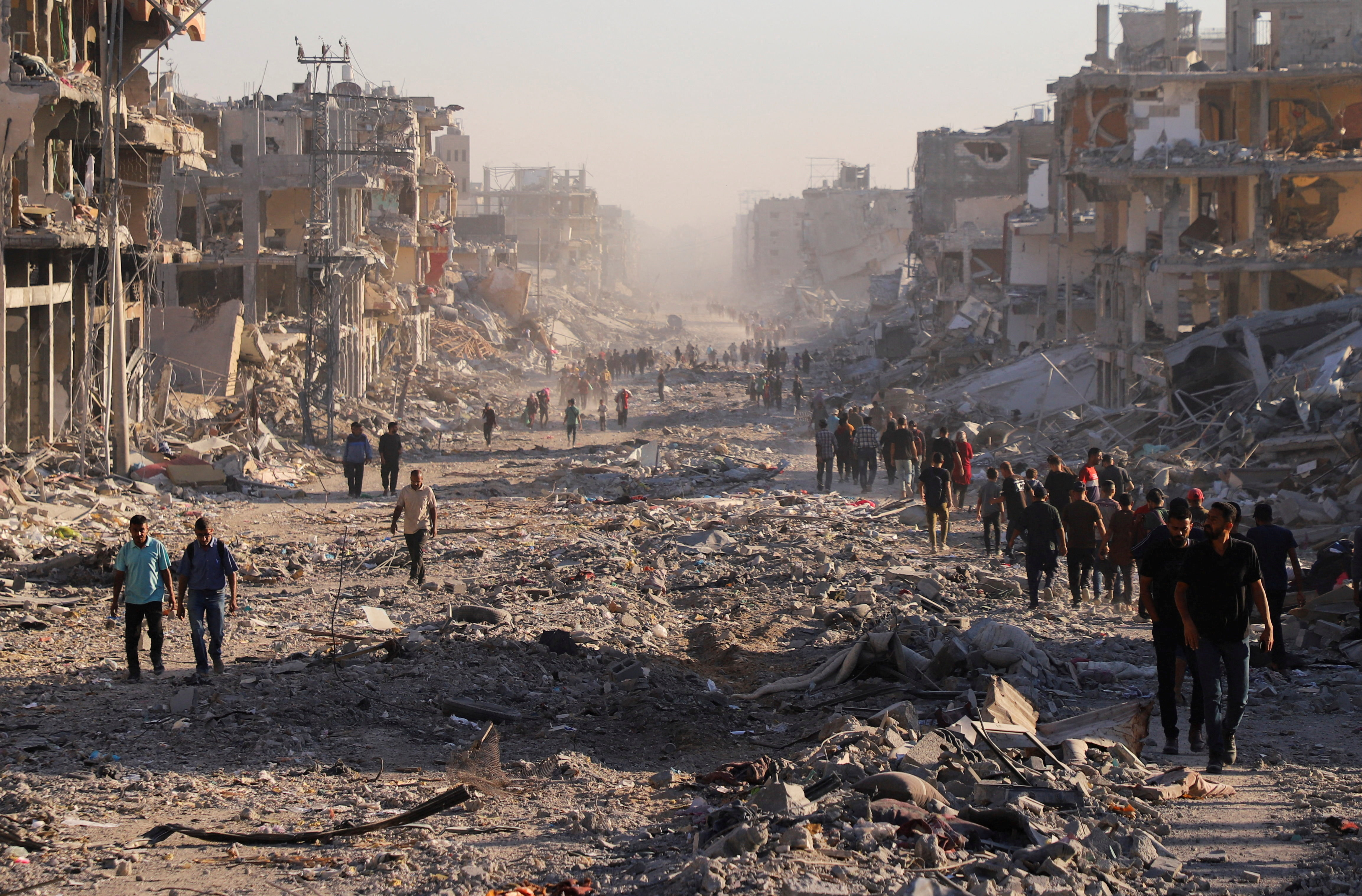 Palestinians walk through a damaged neighborhood in the aftermath of an Israeli operation, after Israel's government ratified a ceasefire with Hamas, in Gaza City October 10, 2025. REUTERS/ Ebrahim Hajjaj
     TPX IMAGES OF THE DAY     