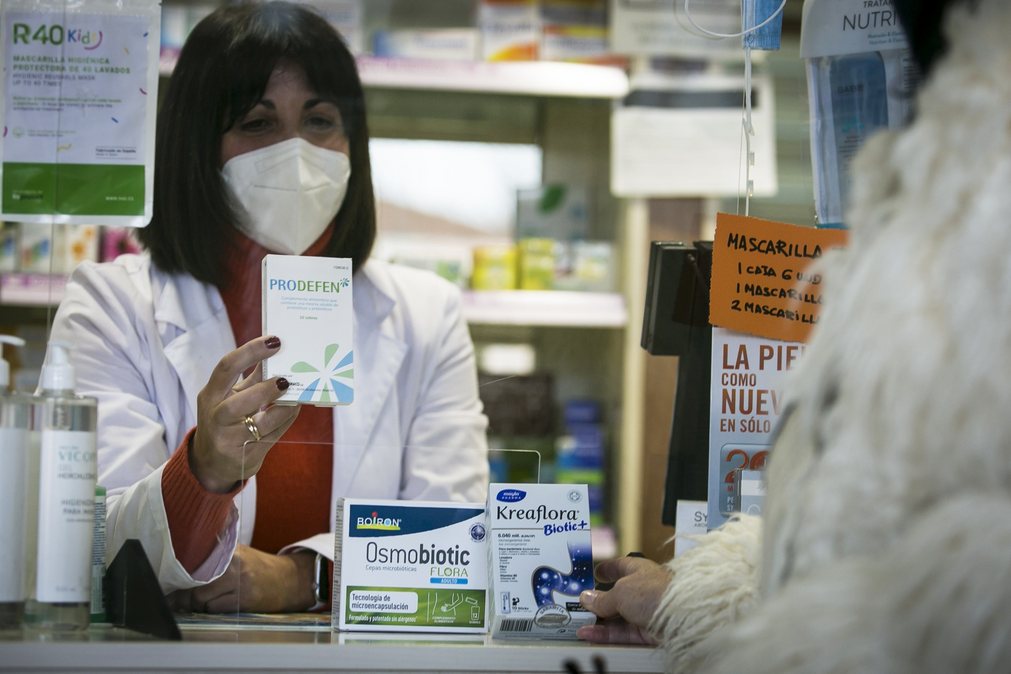 Una farmacéutica dispensa probióticos a un cliente en una botica de Madrid.