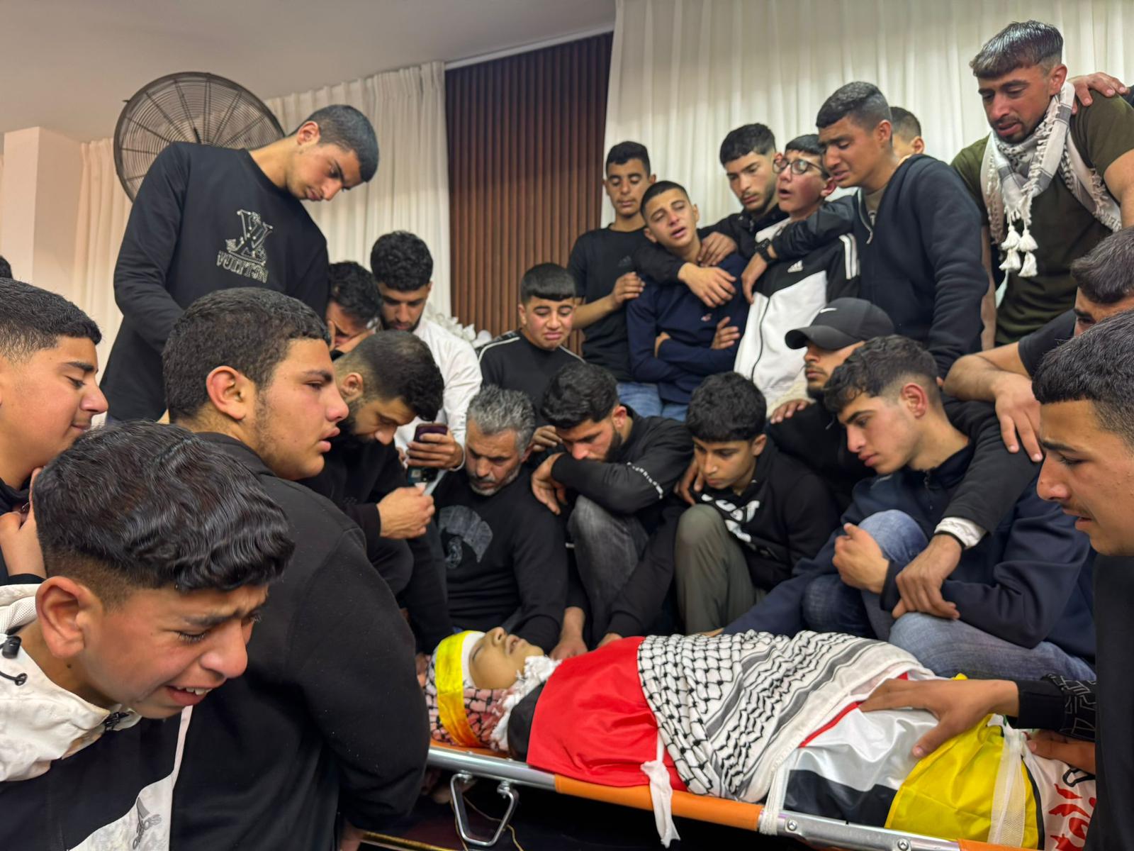 Amigos y compañeros de clase de Aws Hamdi al Nasaan, el adolescente palestino muerto en la víspera por disparos de un colono israelí, velan su cadáver en Al Mugayer, en Cisjordania, este miércoles.
