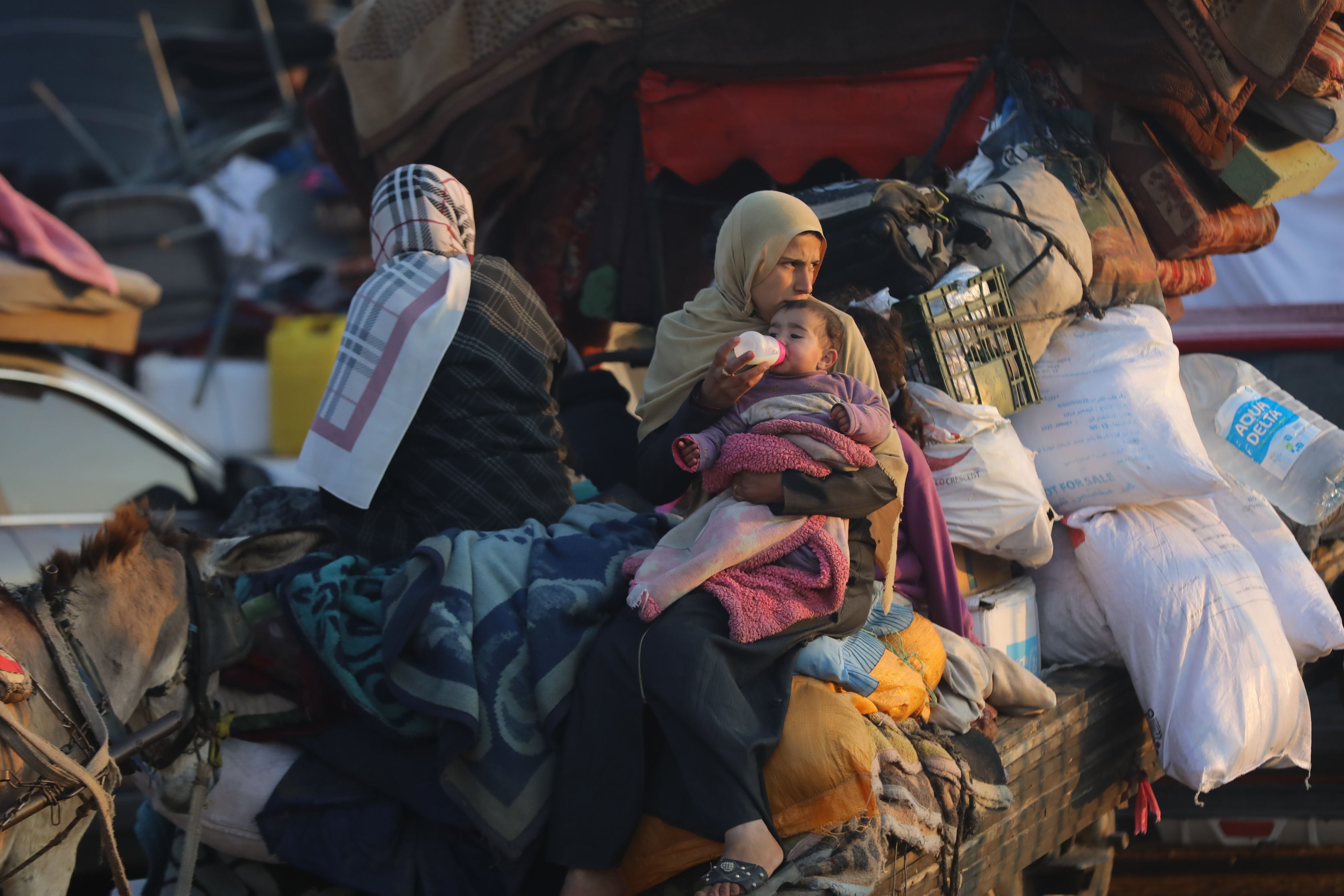 Dos mujeres palestinas sentadas sobre sus pertenencias en el camino hacia el norte de la Franja, este mircoles 29 de enero de 2025