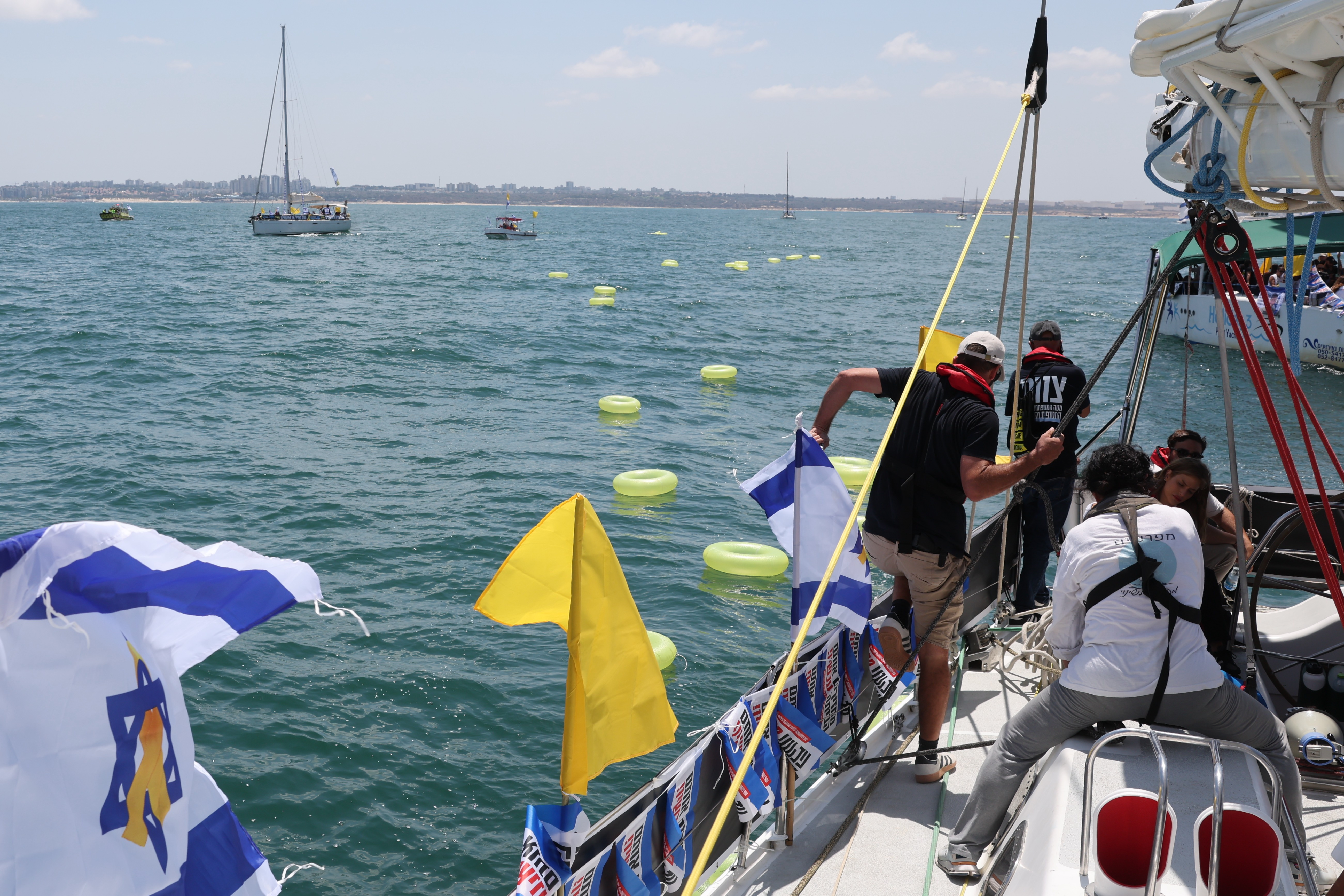 Familiares de rehenes israelíes lanzan flotadores amarillos mientras navegan en una flotilla que exige su liberación inmediata frente a la frontera marítima con la Franja 