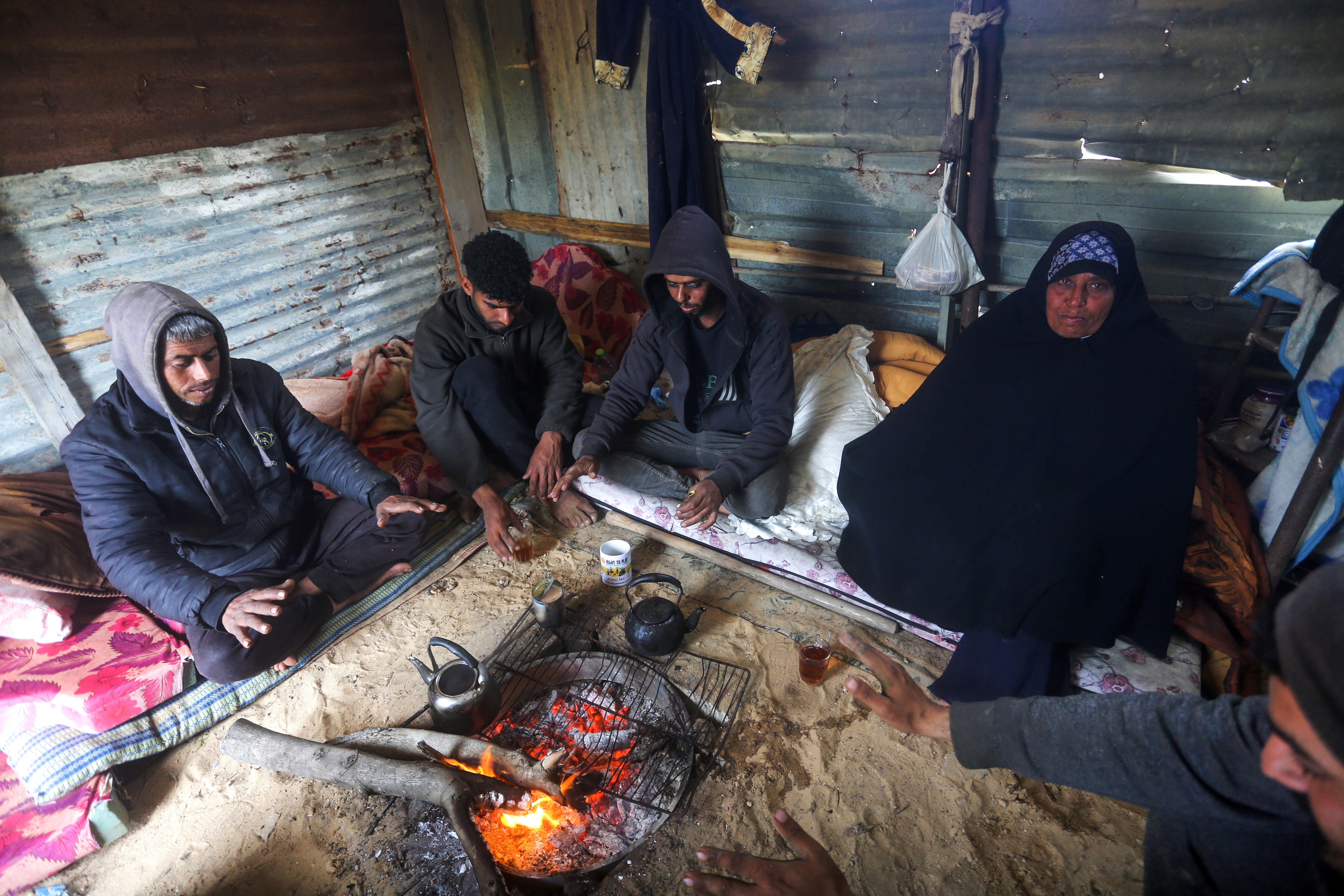 Una familia gazat se refugia del fro en un campamento hechizo, en la localidad de Al Mughraqa, en el centro de la Franja, este mircoles 12 de febrero de 2025.