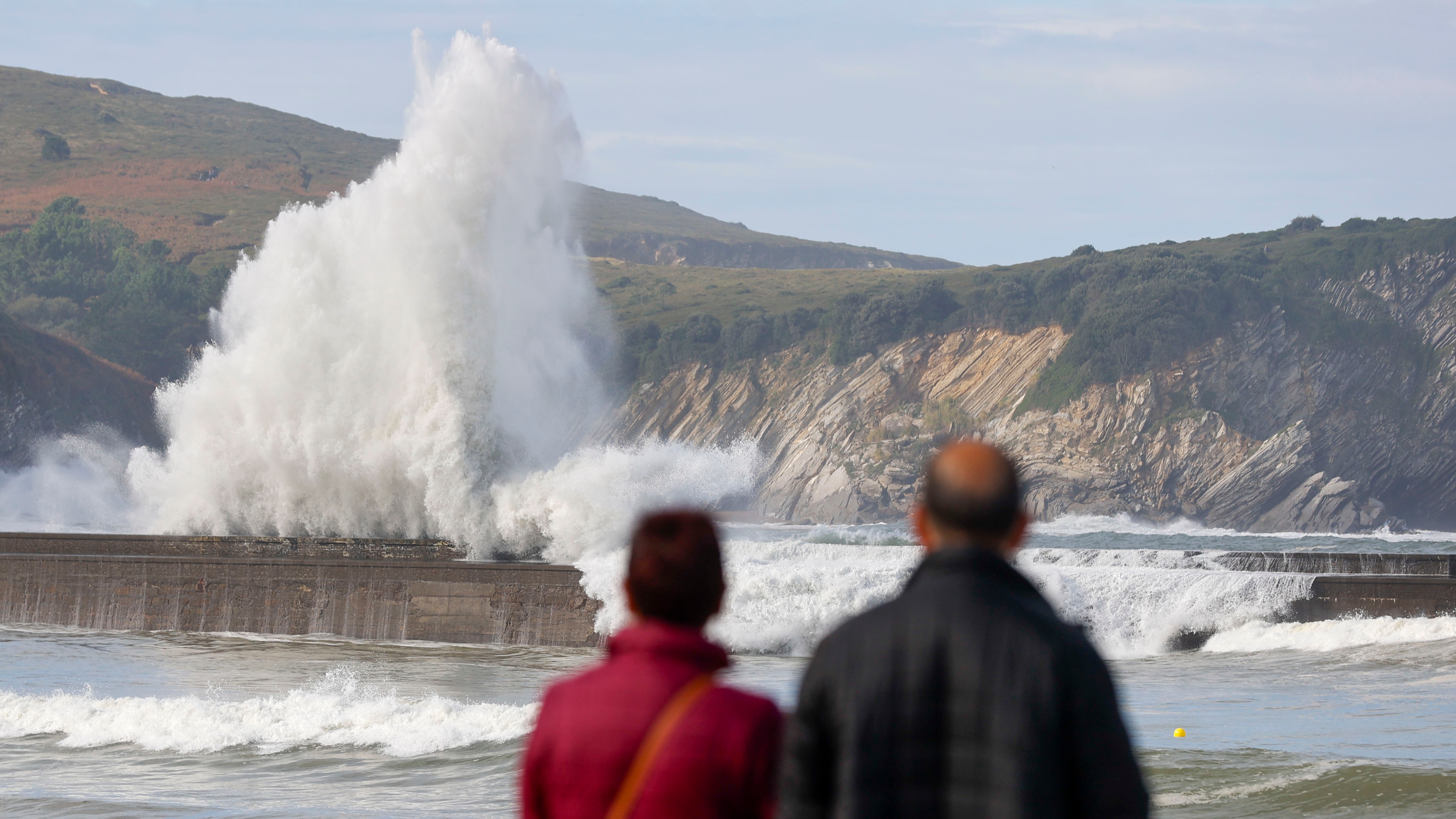 Dos personas observan el domingo cómo rompen la olas en la localidad vizcaína de Plentzia.