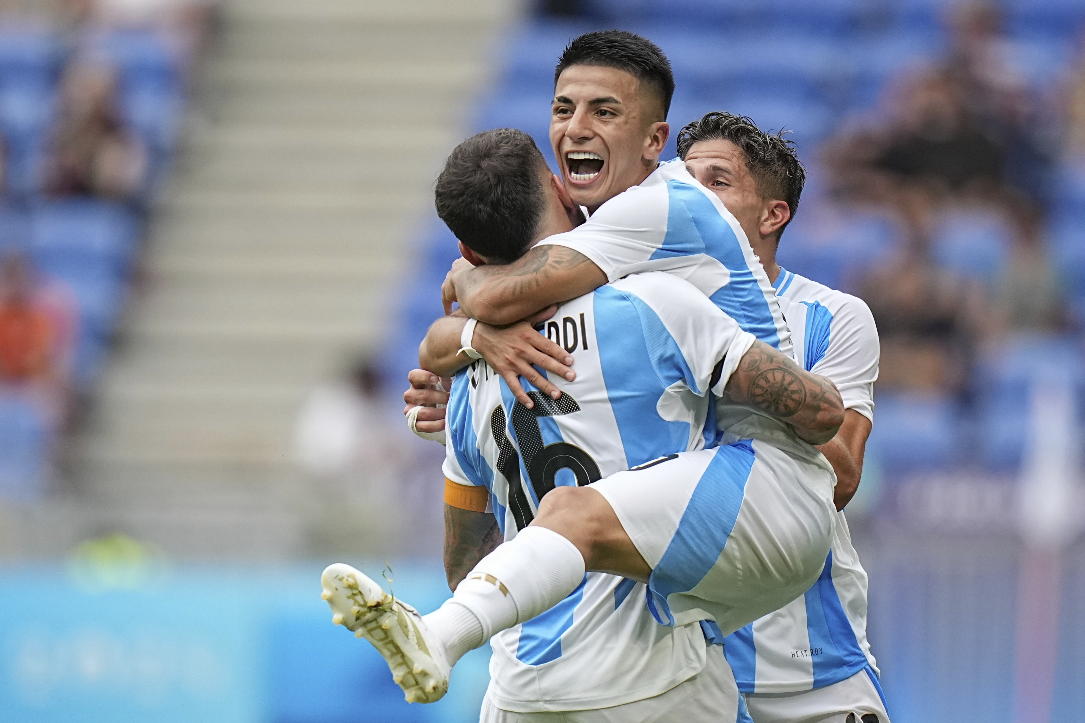 Argentina's Thiago Almada celebrates with Nicolas Otamendi scoring his side's opening goal against Ukraine during the men's Group B soccer match at the Lyon stadium during the 2024 Summer Olympics, Tuesday, July 30, 2024, in Decines, France. (AP Photo/Laurent Cipriani)