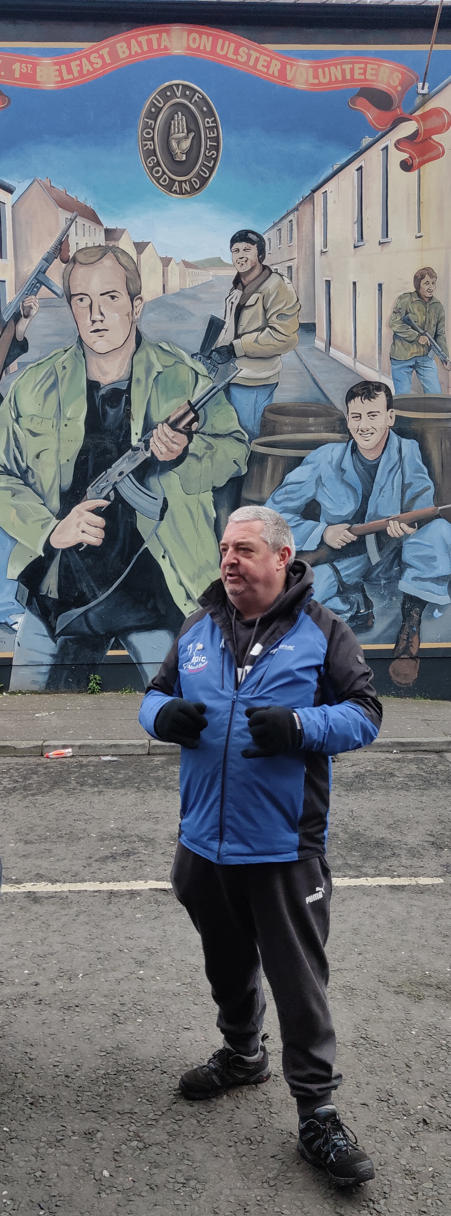 Mark, o guia turístico unionista de Belfast, em frente a um mural no bairro protestante