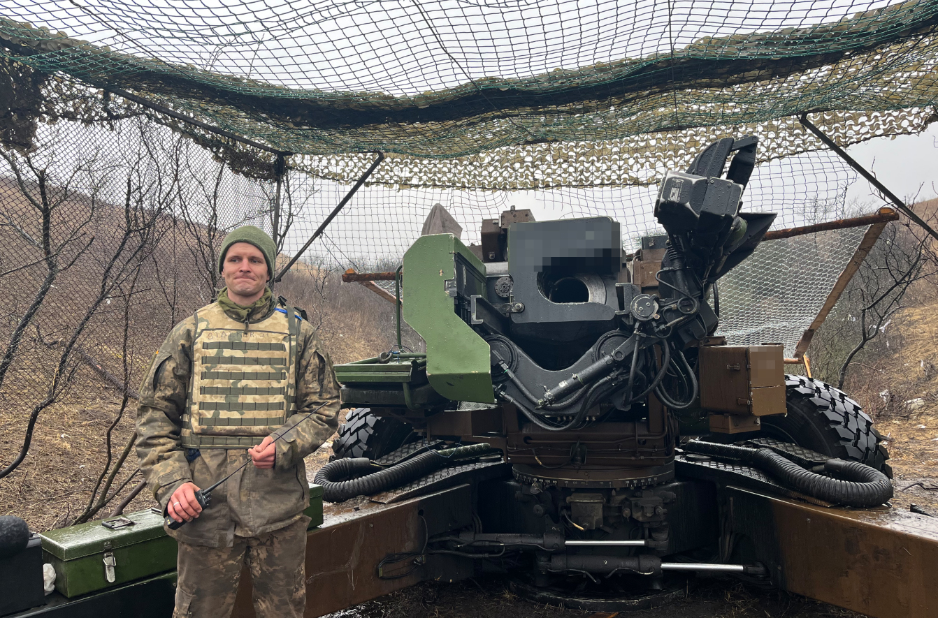 Um soldado ucraniano, ao lado de um canhão francês Howitzer TRFI.