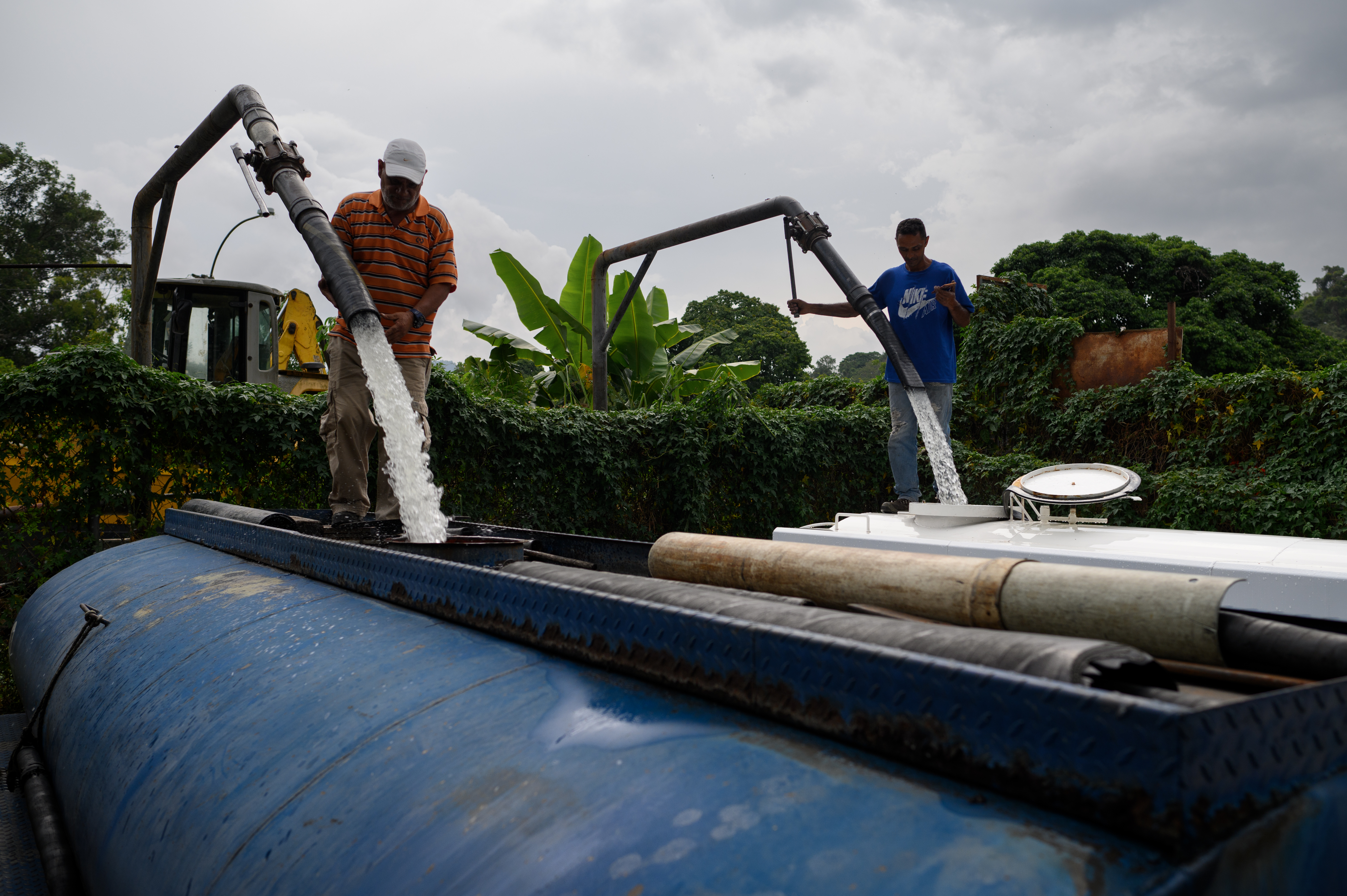 Trabalhadores enchem caminhões-tanque de água privados em Caracas, Venezuela.