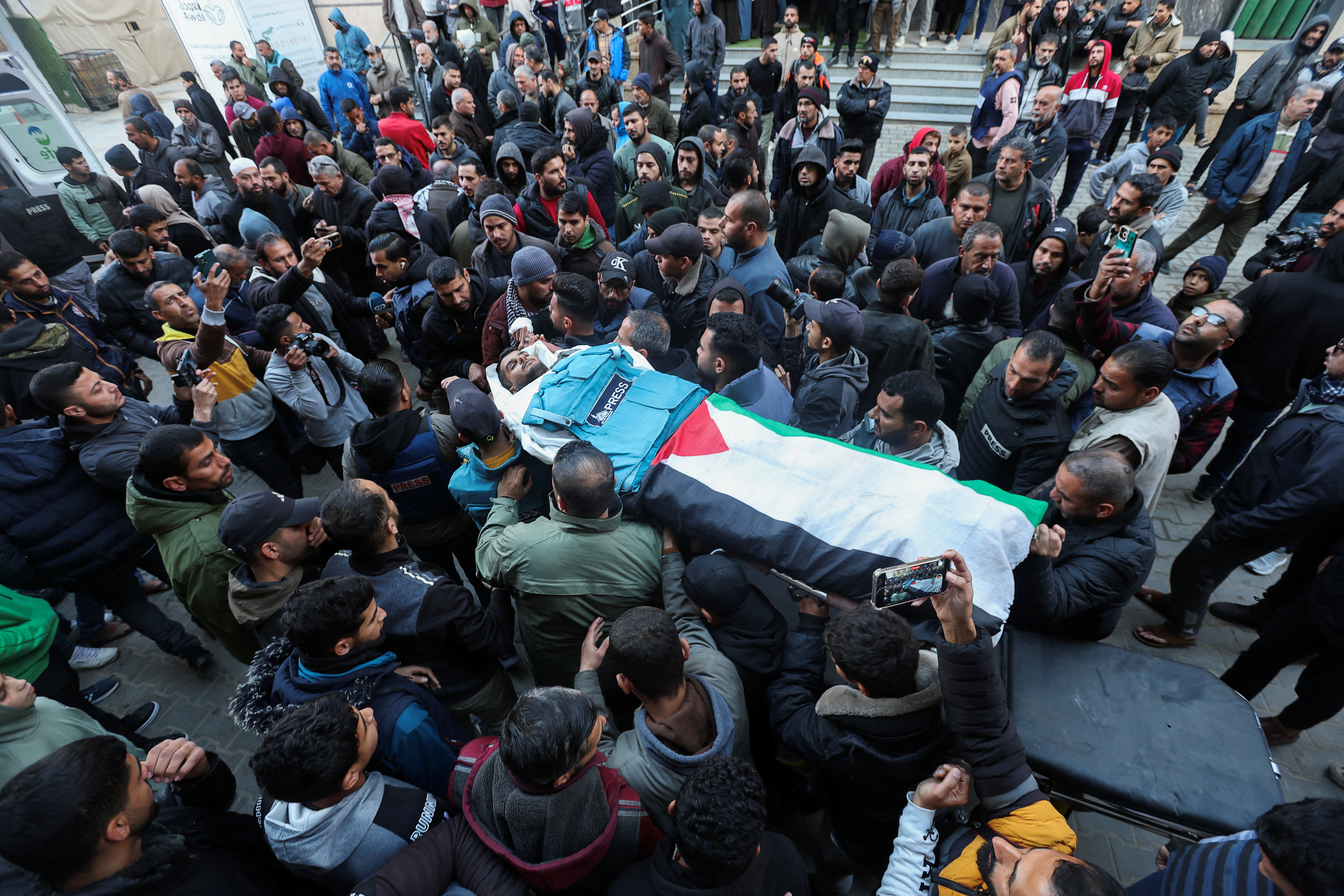 Ciudadanos palestinos cargan este sábado el cuerpo de Saed Nabhan, periodista que fue asesinado por fuego israelí mientras cubría un incidente en el campo de refugiados de Nuseirat, en Gaza.