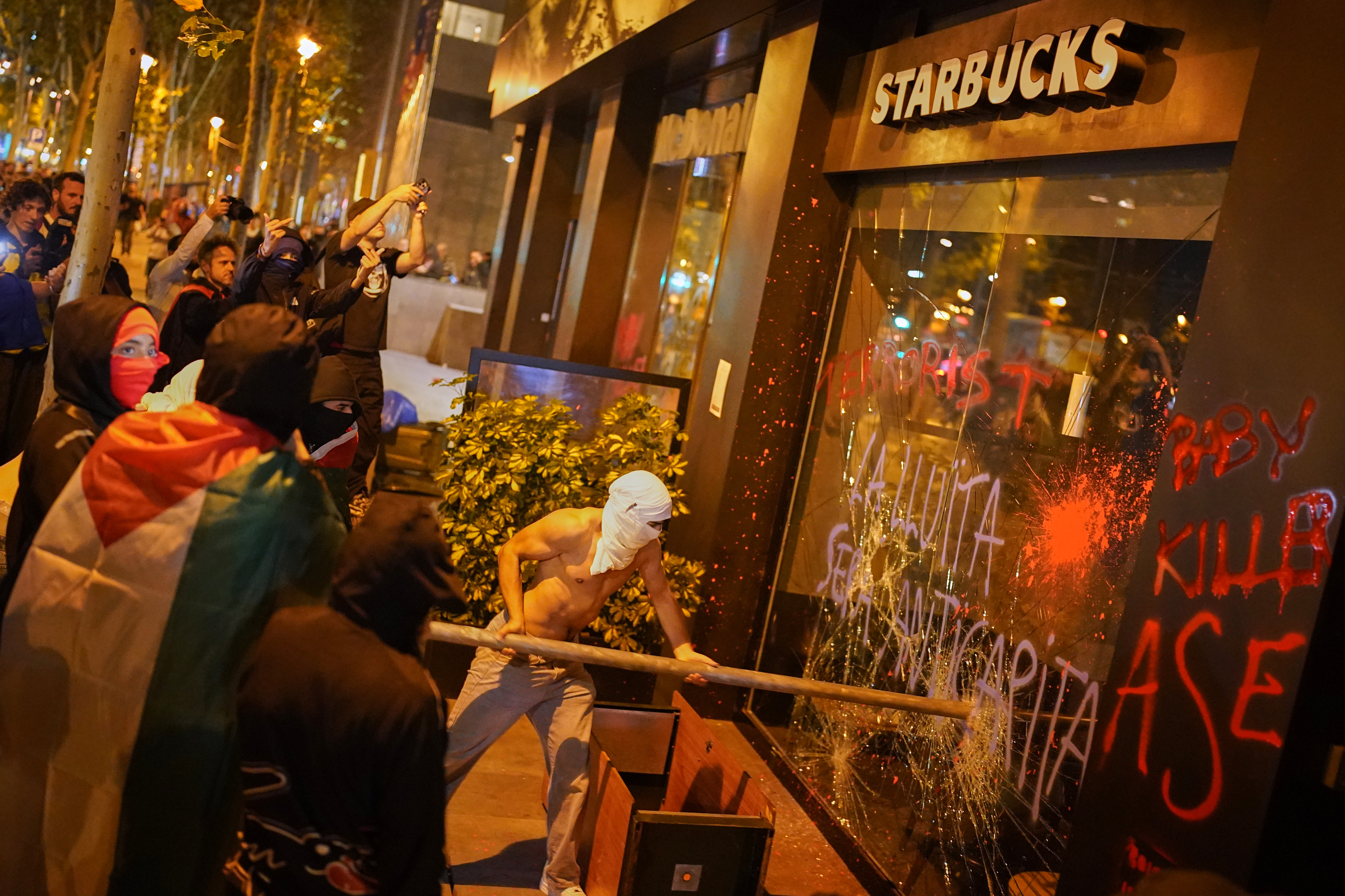 Demonstrators break the shop window of a Starbucks during a protest in support of Palestinians and protesting Israel's actions, in Barcelona, Wednesday, Oct. 15, 2025. (AP Photo/Joan Mateu Parra)