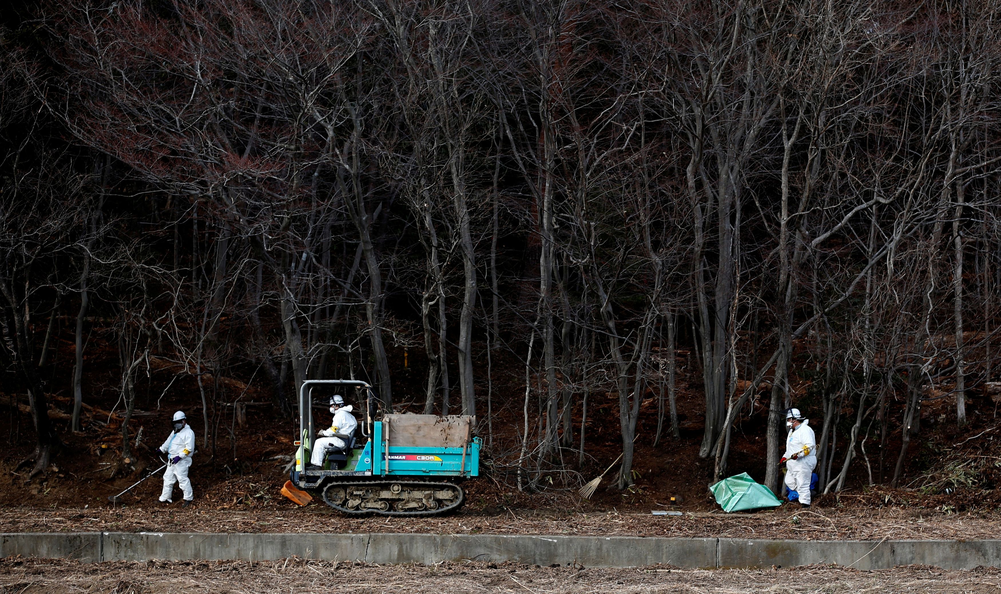 FILE PHOTO: Decontamination workers wearing protective suits and masks, remove radiated soil and leaves from a forest in Tomioka town, Fukushima prefecture, near Tokyo Electric Power Co's (TEPCO) tsunami-crippled Fukushima Daiichi nuclear power plant February 24, 2015. REUTERS/Toru Hanai/File Photo SEARCH 