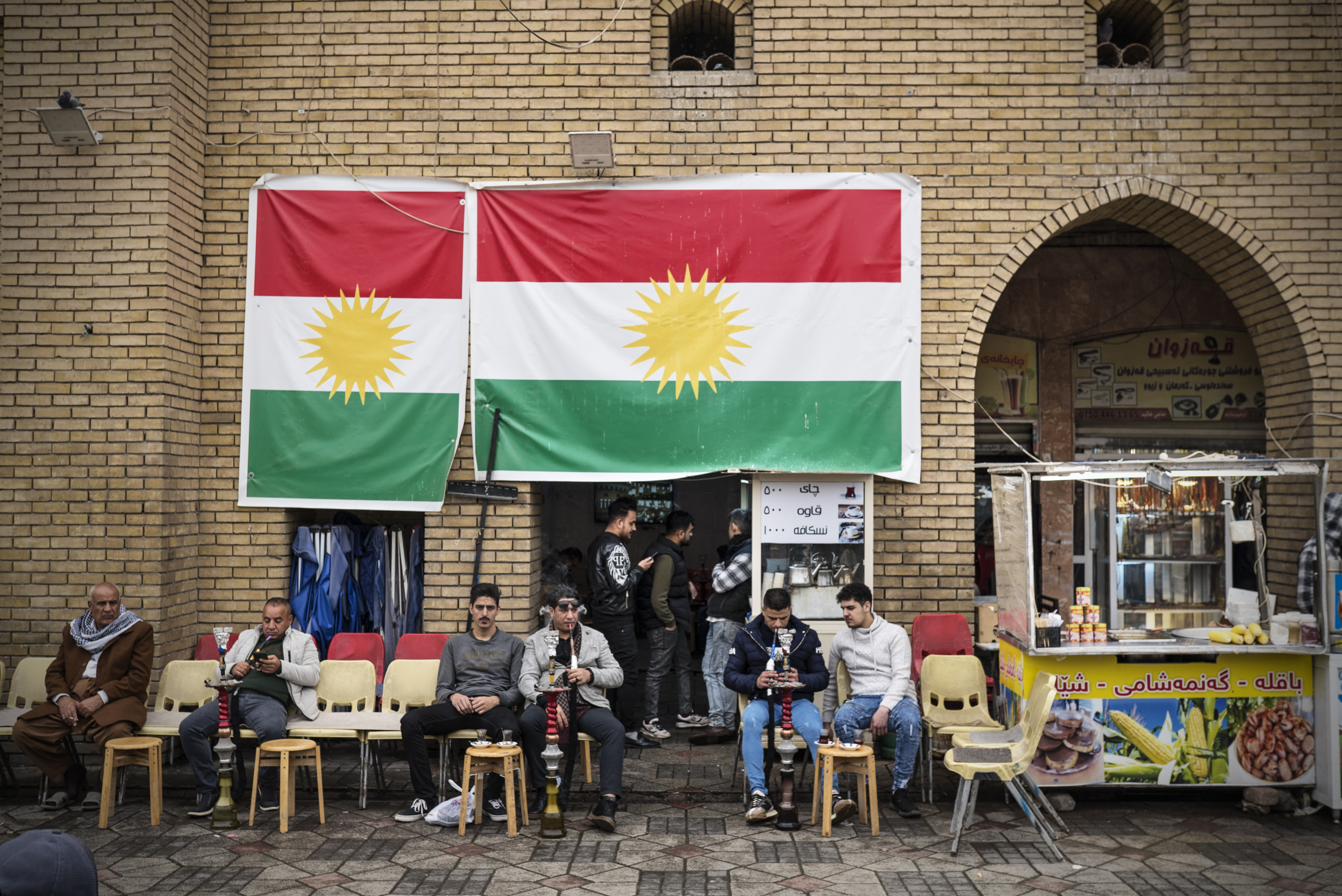 Jovens fumam narguilé sob duas bandeiras do Curdistão iraquiano em Erbil, capital da região de mesmo nome e que goza de ampla autonomia em relação ao governo federal iraquiano.
