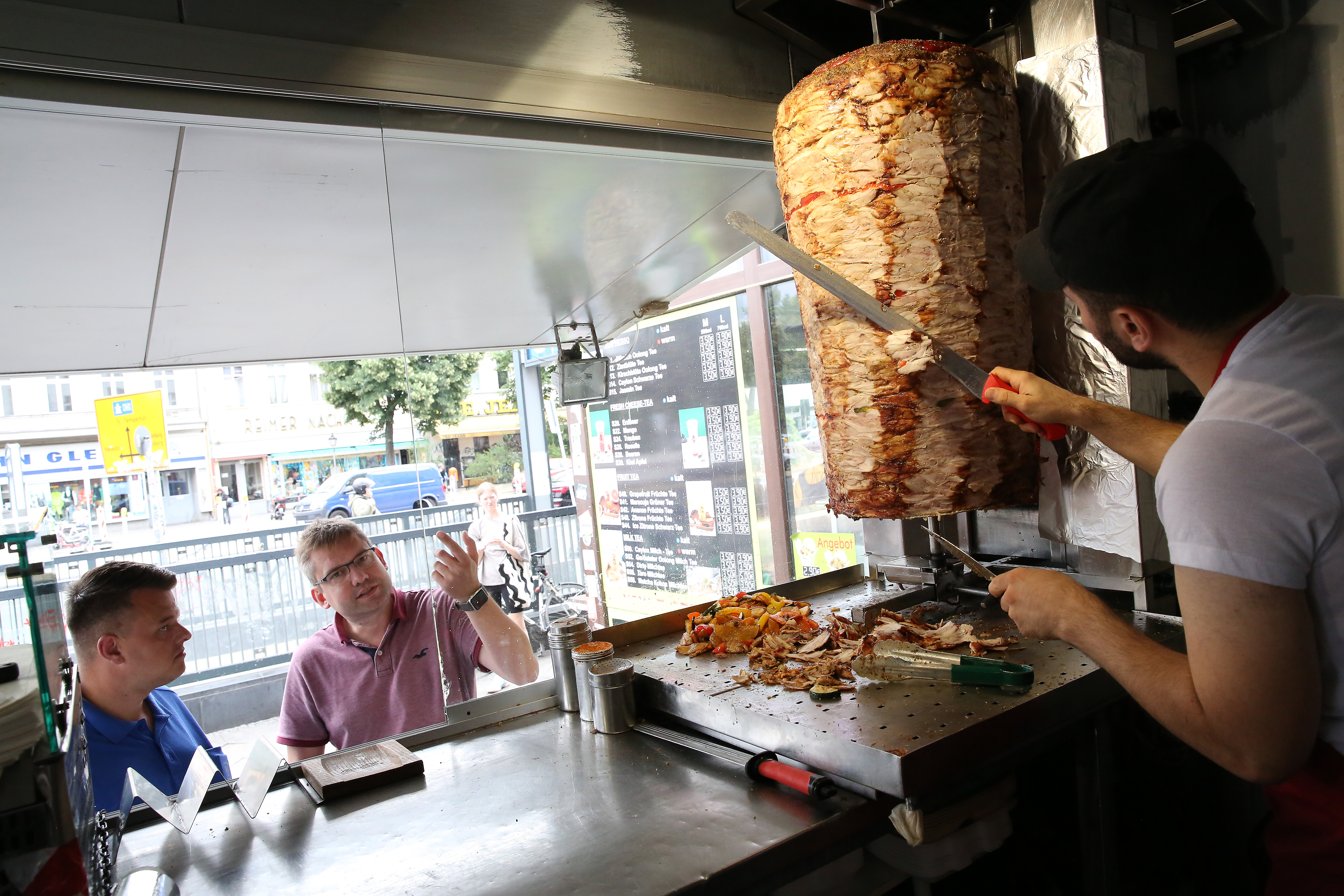 BERLIN, GERMANY - JULY 06: An employee prepares a customer's order at Mustafas Gemüse Kebap on July 06, 2022 in Berlin, Germany. The döner kebab, a fast food sandwich made of stacked, seasoned meat turned on a rotisserie, was popularized in Germany in the early 1970s by Turkish guest workers (Gastarbeiter in German, or migrants arriving in Germany after World War II to counter labor shortages), with more stands offering the dish in Berlin than in Istanbul, and many considering it to be Germany's national dish.