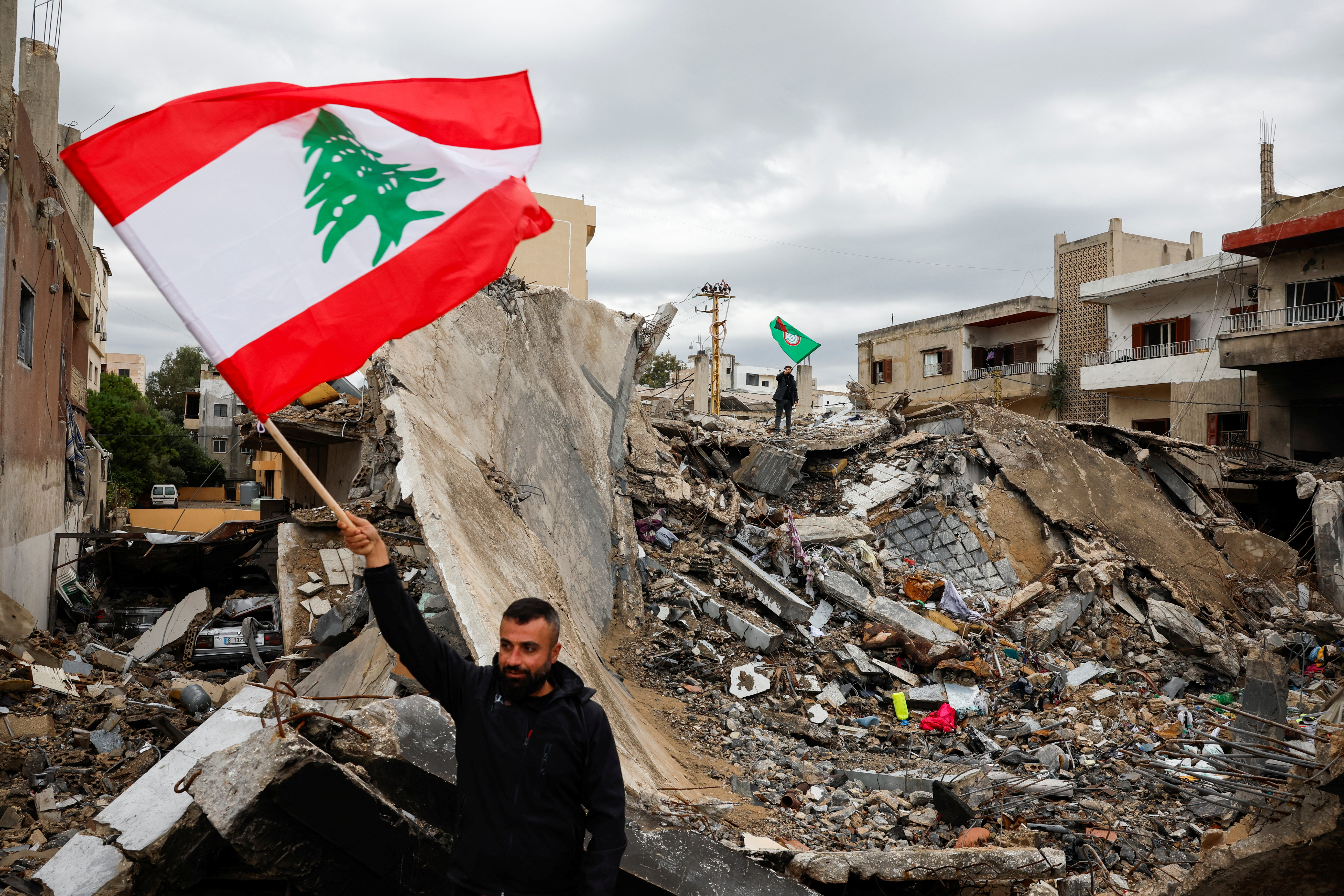 Un hombre ondea una bandera de Líbano frente a los escombros de un edificio destruido por ataques israelíes, este 27 de noviembre de 2024