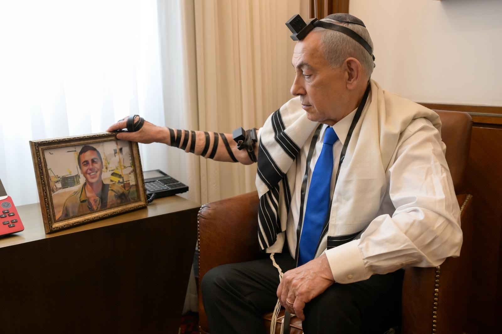 El primer ministro israelí, Benjamin Netanyahu, en su despacho este martes 21 de abril, sostiene una foto del sargento Sean Carmeli, fallecido durante la invasión israelí en Gaza, en 2014.