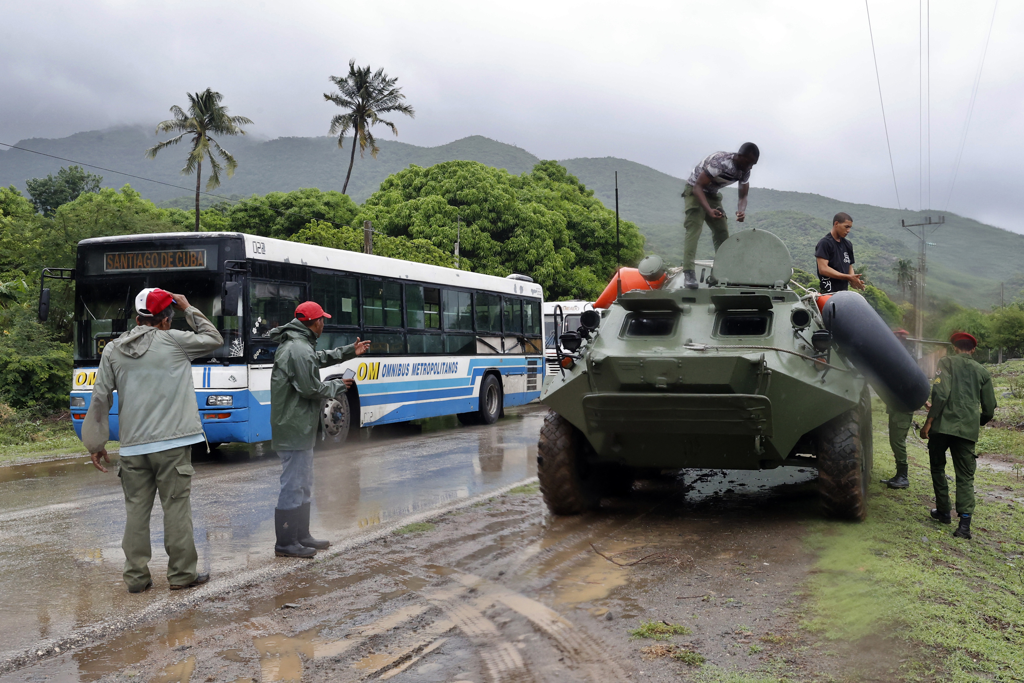 Miembros de la Policía y las Fuerzas Armadas Revolucionarias colaboran este martes en las labores de evacuación de personas en una carretera de Santiago de Cuba.