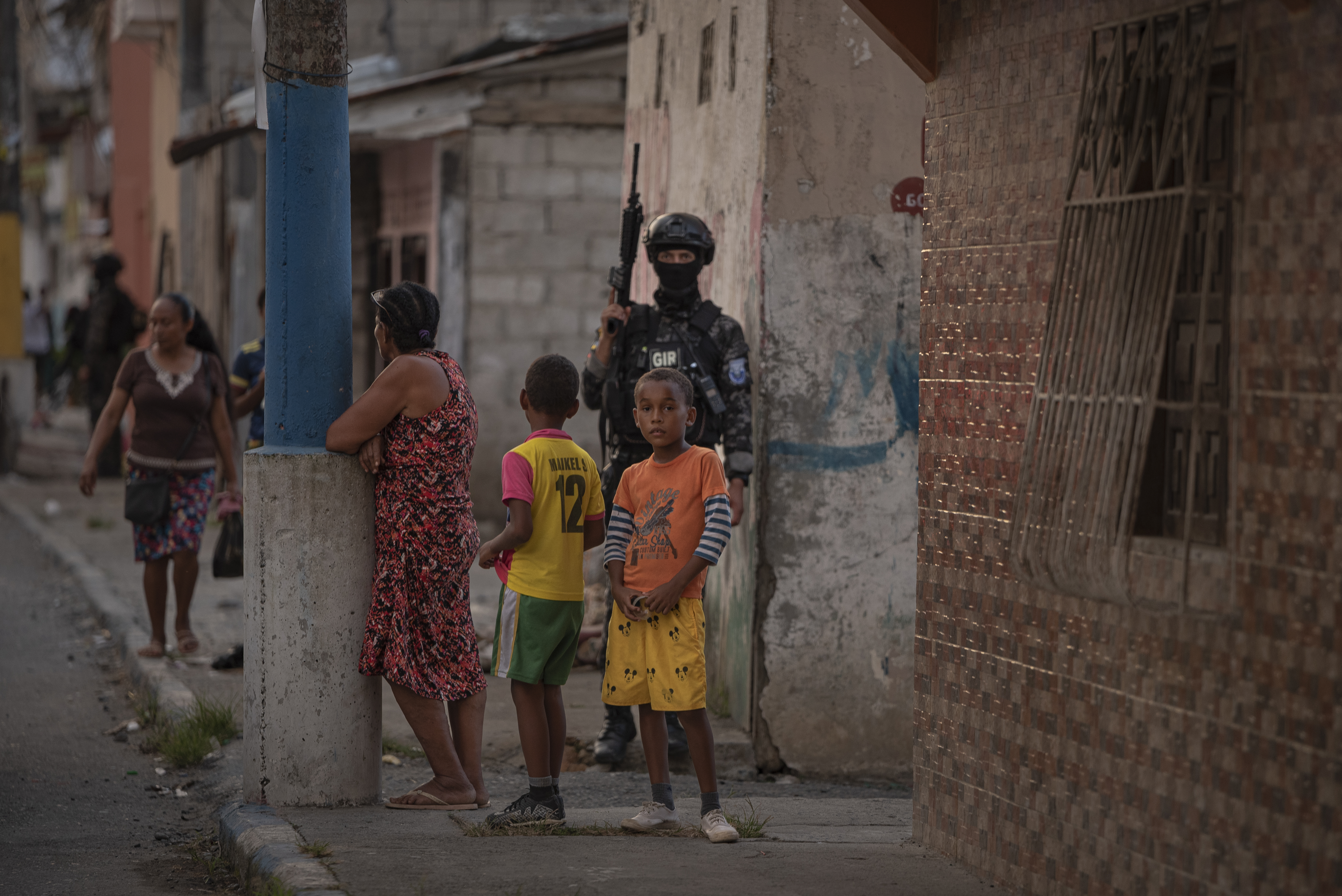 Escoltados por um policial, uma mulher e duas crianças observam a operação de controle em Esmeraldas.
