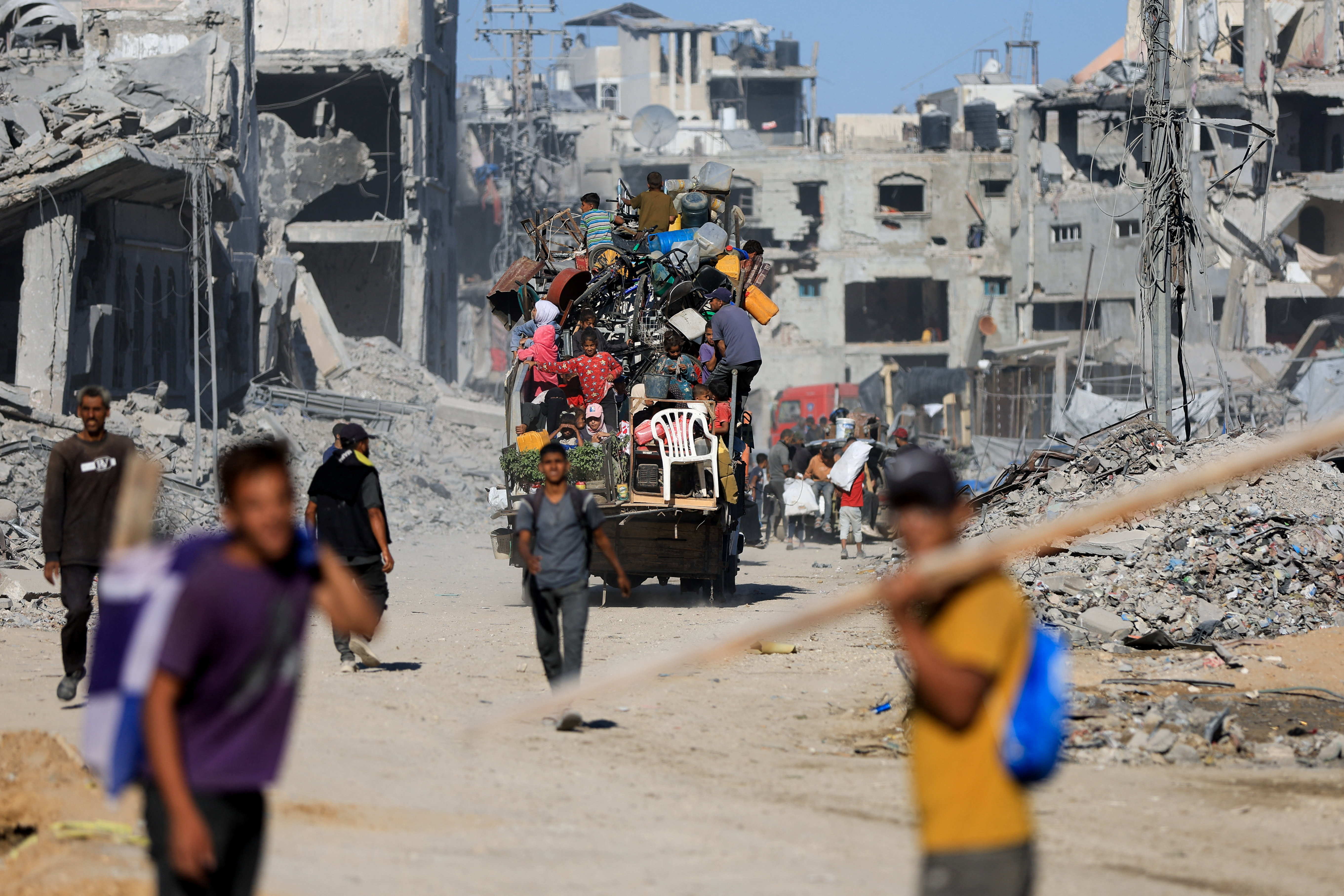 Palestinians pass by the rubble of destroyed buildings, amid a ceasefire between Israel and Hamas, in Gaza City, October 14, 2025. REUTERS/Dawoud Abu Alkas
