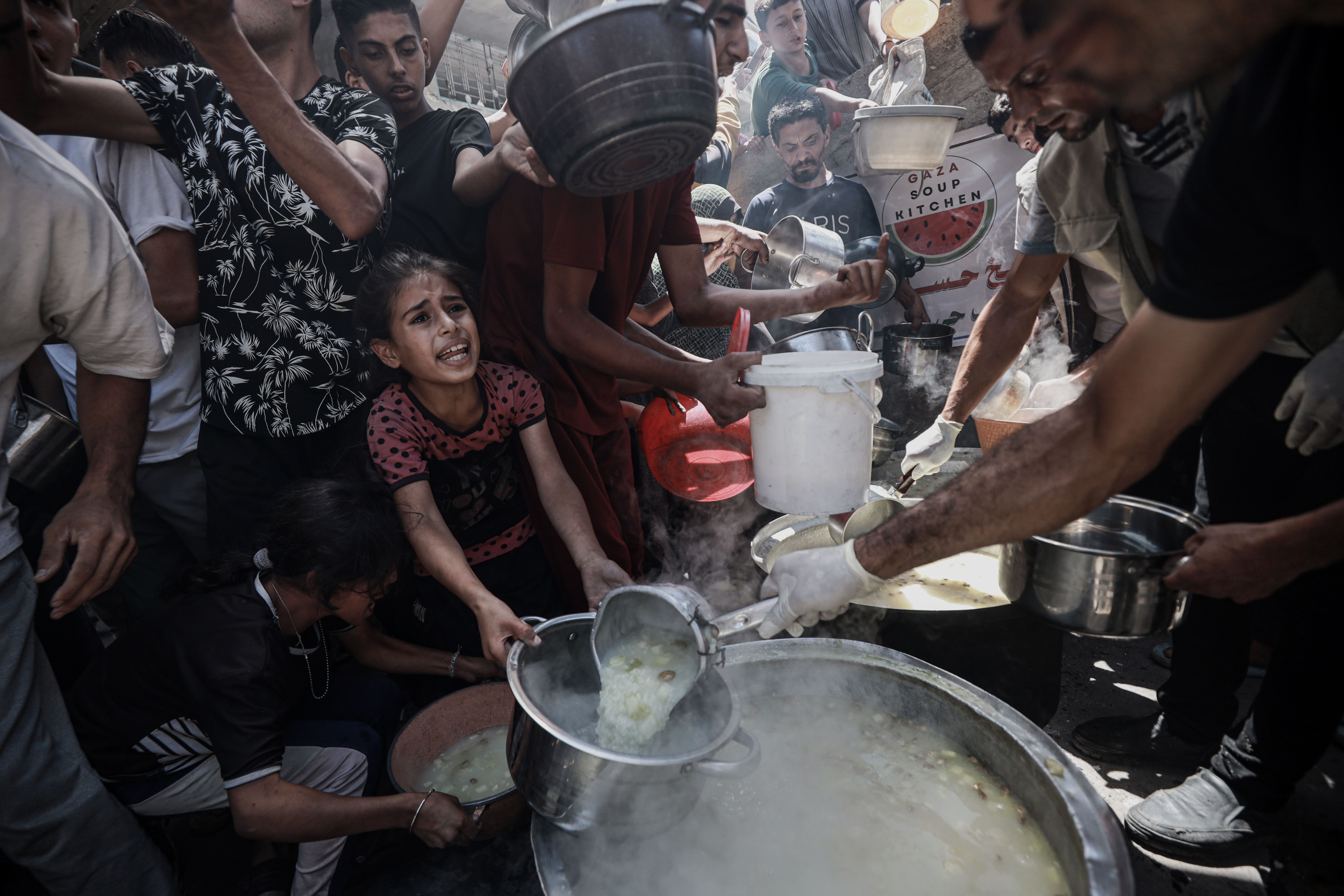 Decenas de personas tratan desesperadamente de lograr comida en Ciudad de Gaza.