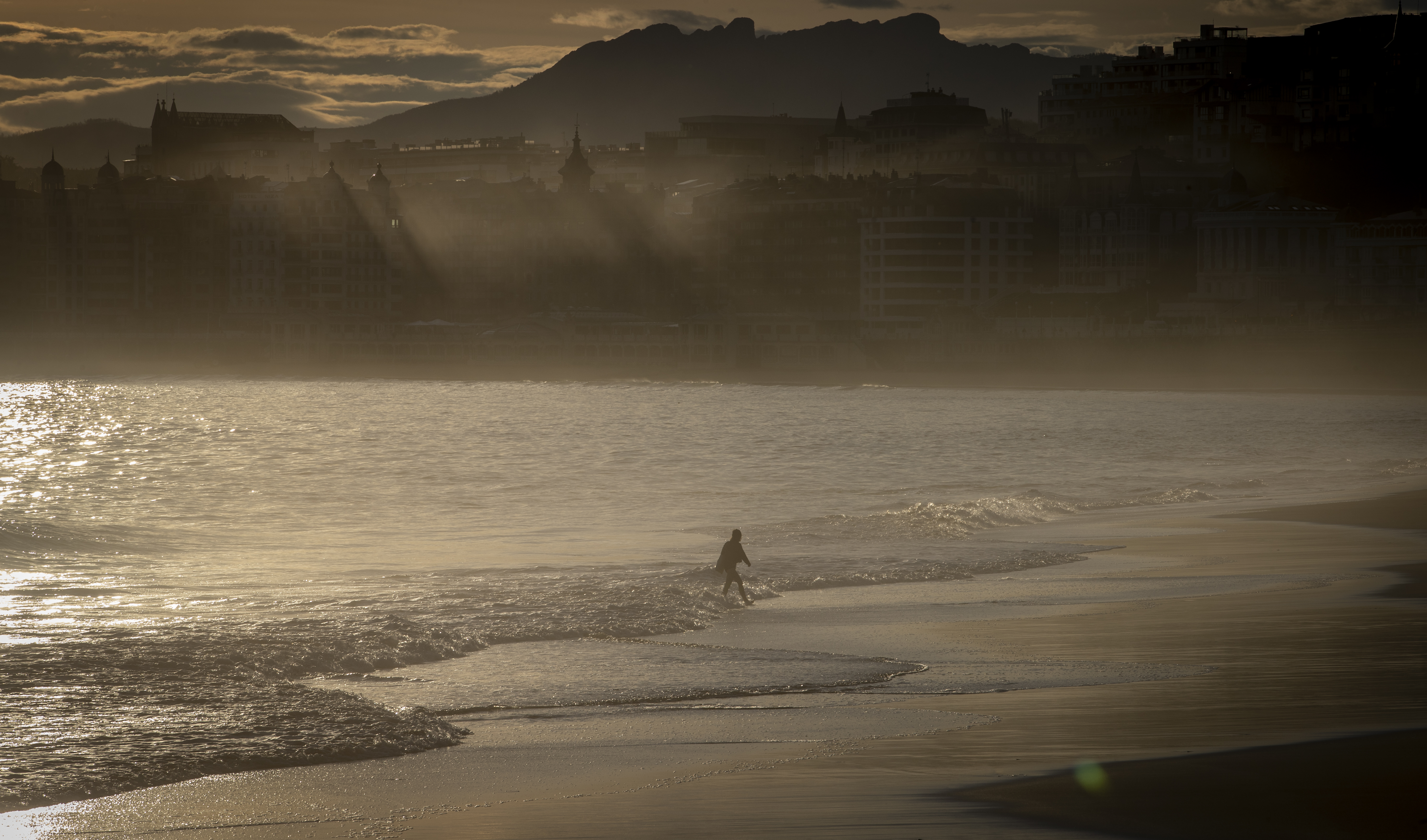 Una mujer pasea a primera hora de este jueves por la orilla de la playa de Ondarreta de San Sebastián.