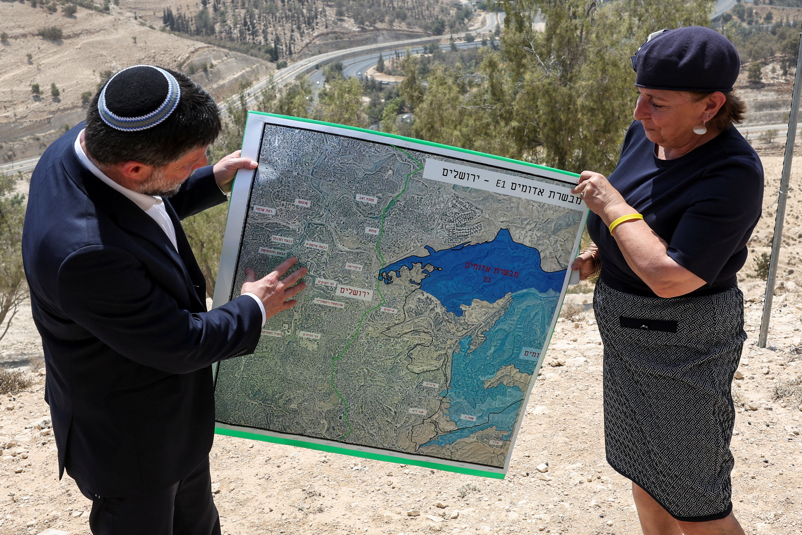El ministro de Finanzas israelí, Bezalel Smotrich y una mujer, sostienen el mapa del proyecto E1, en Cisrjodania ocupada en agosto de este año.