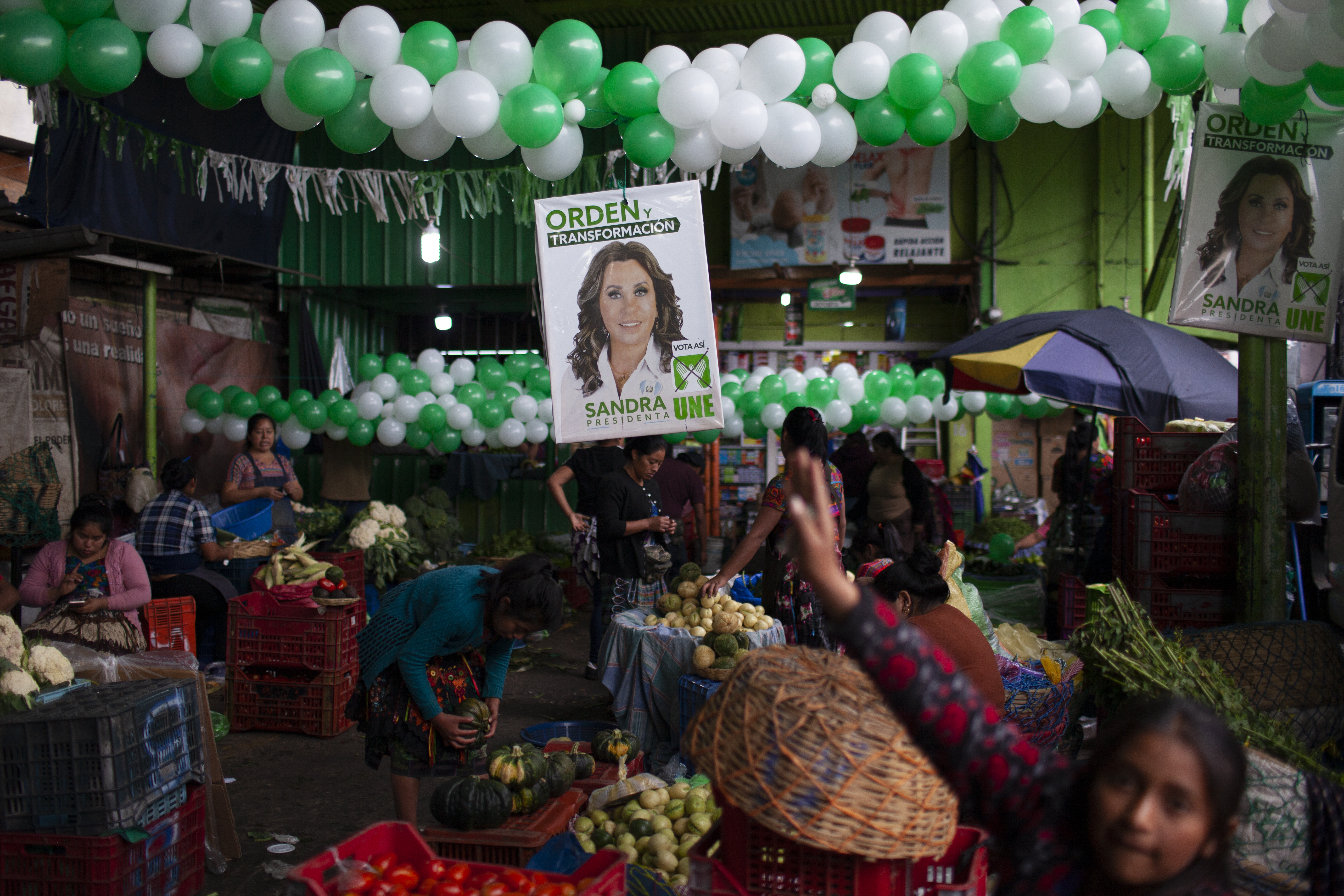 Vendedores da La Terminal trabalham em frente a um pôster de Sandra Torres em 18 de agosto na Cidade da Guatemala.